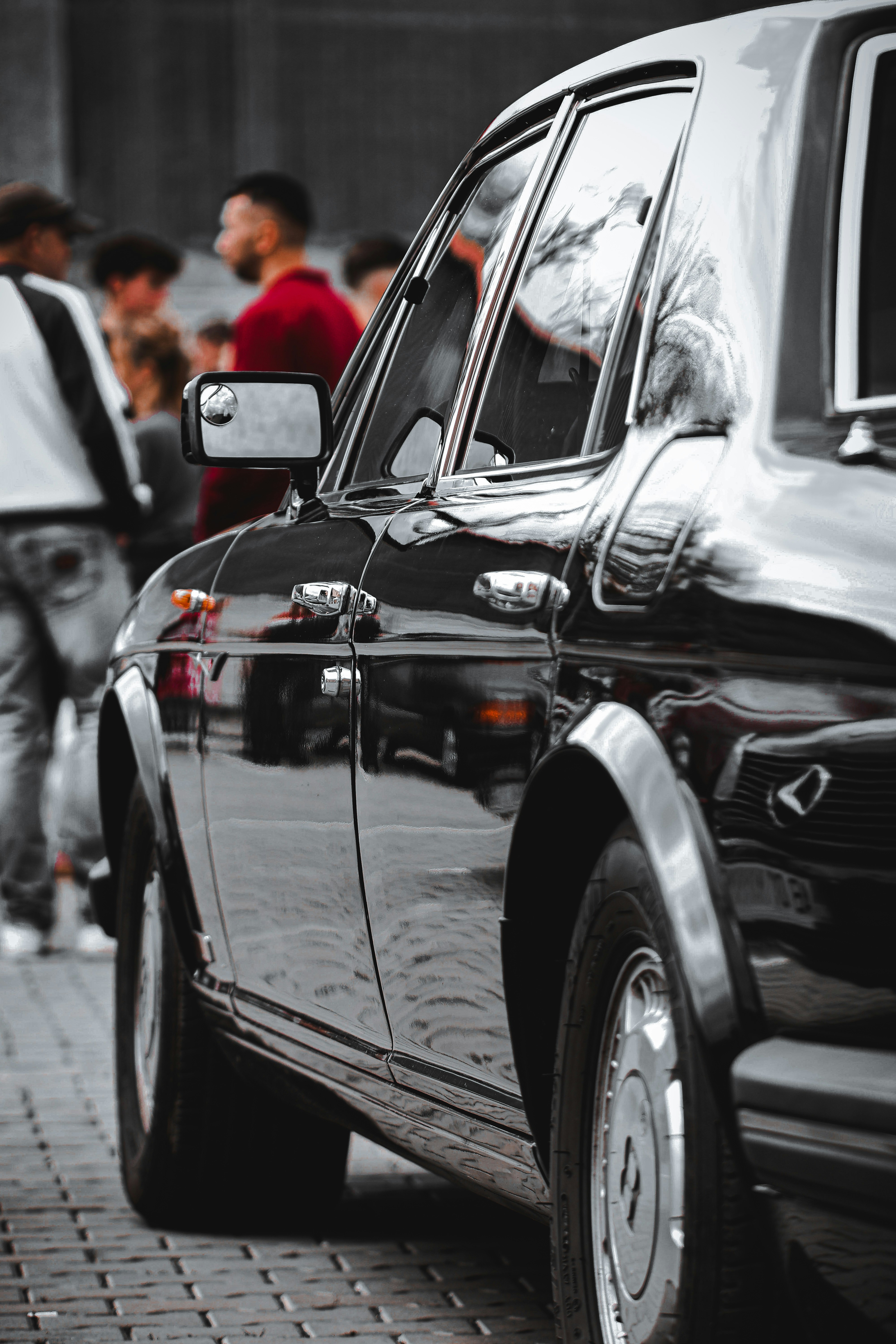 Shiny, black car parked on a cobblestone street.