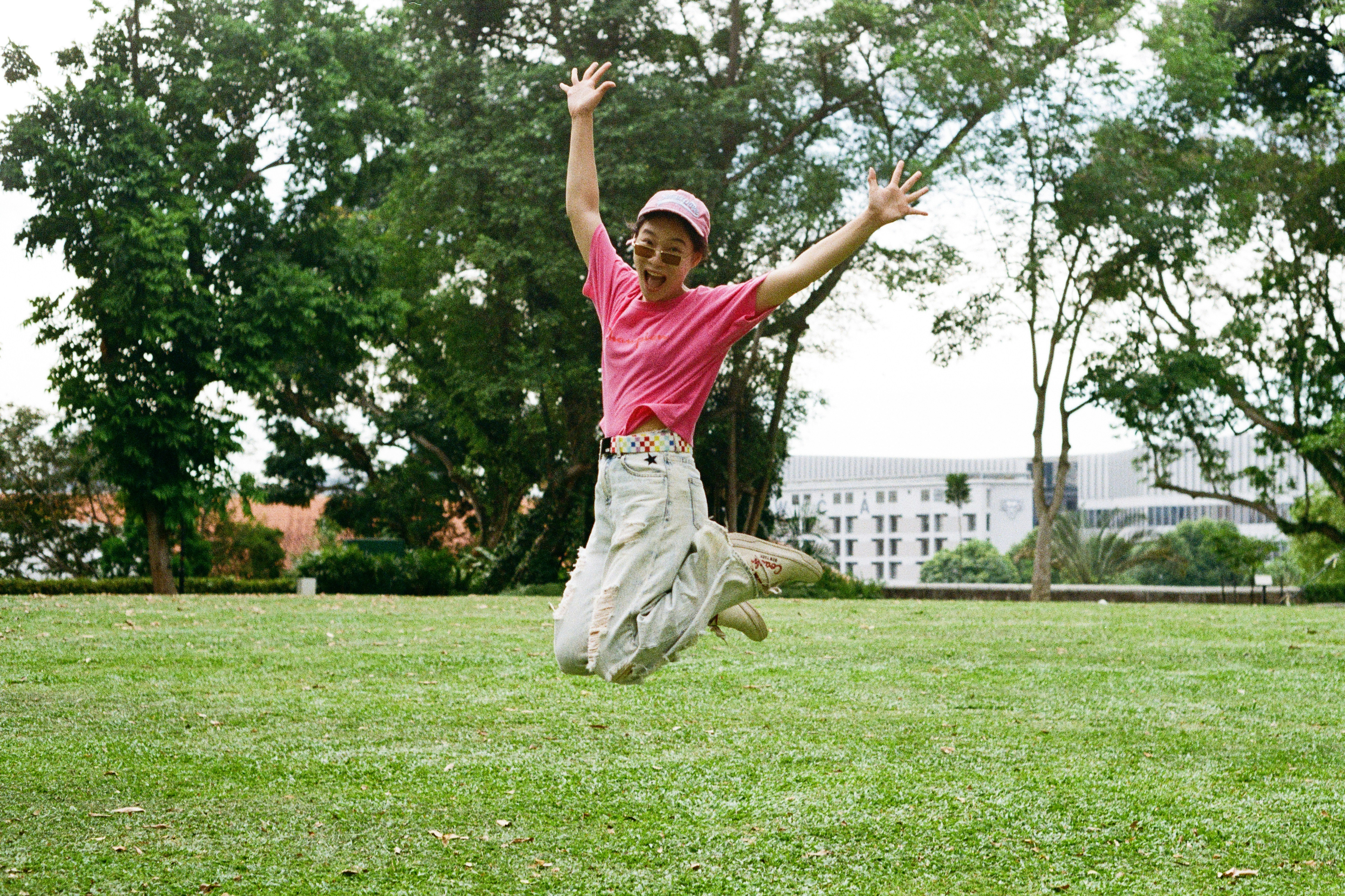 A woman jumps joyfully in a park.