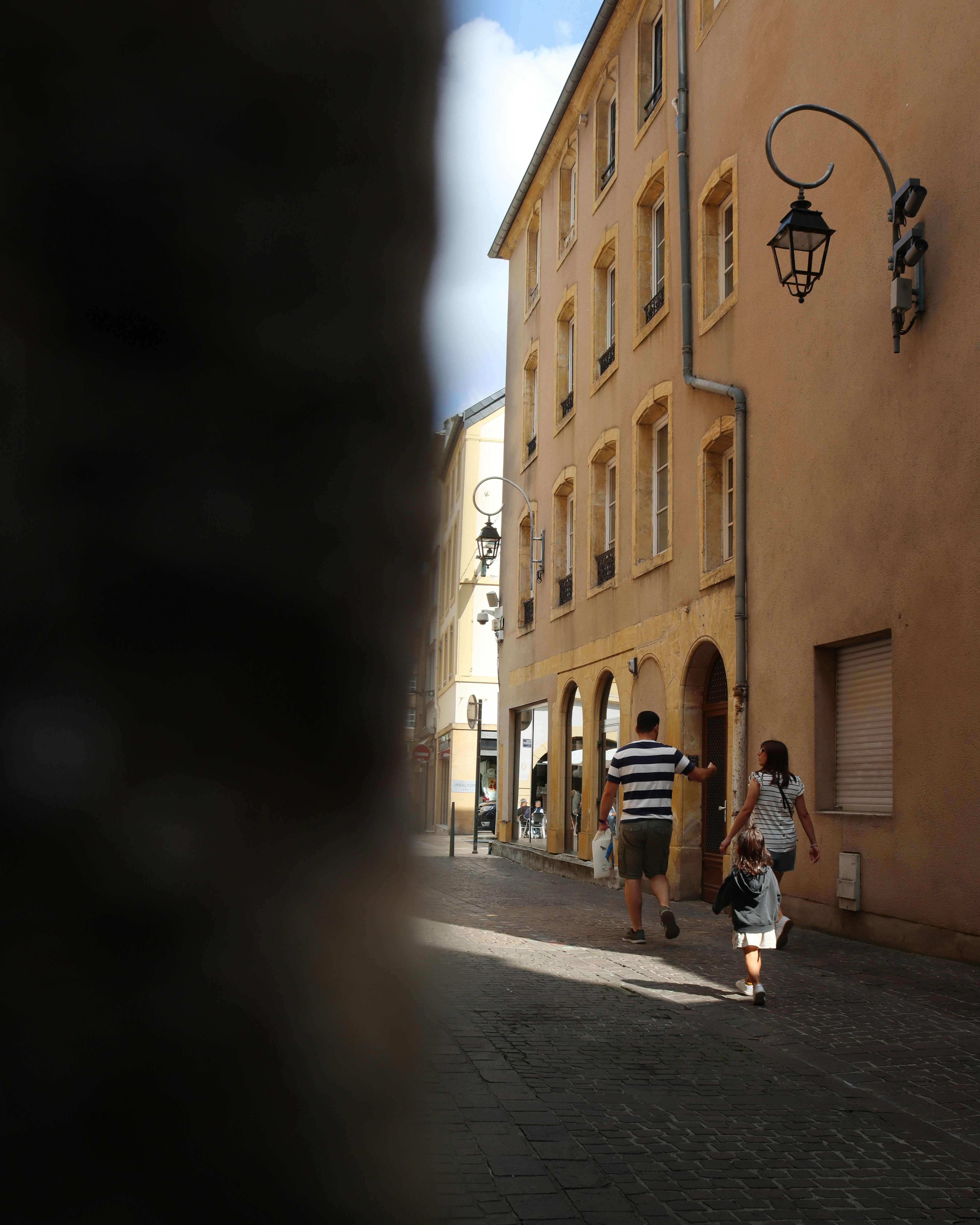 Family walks down a sunny european street.