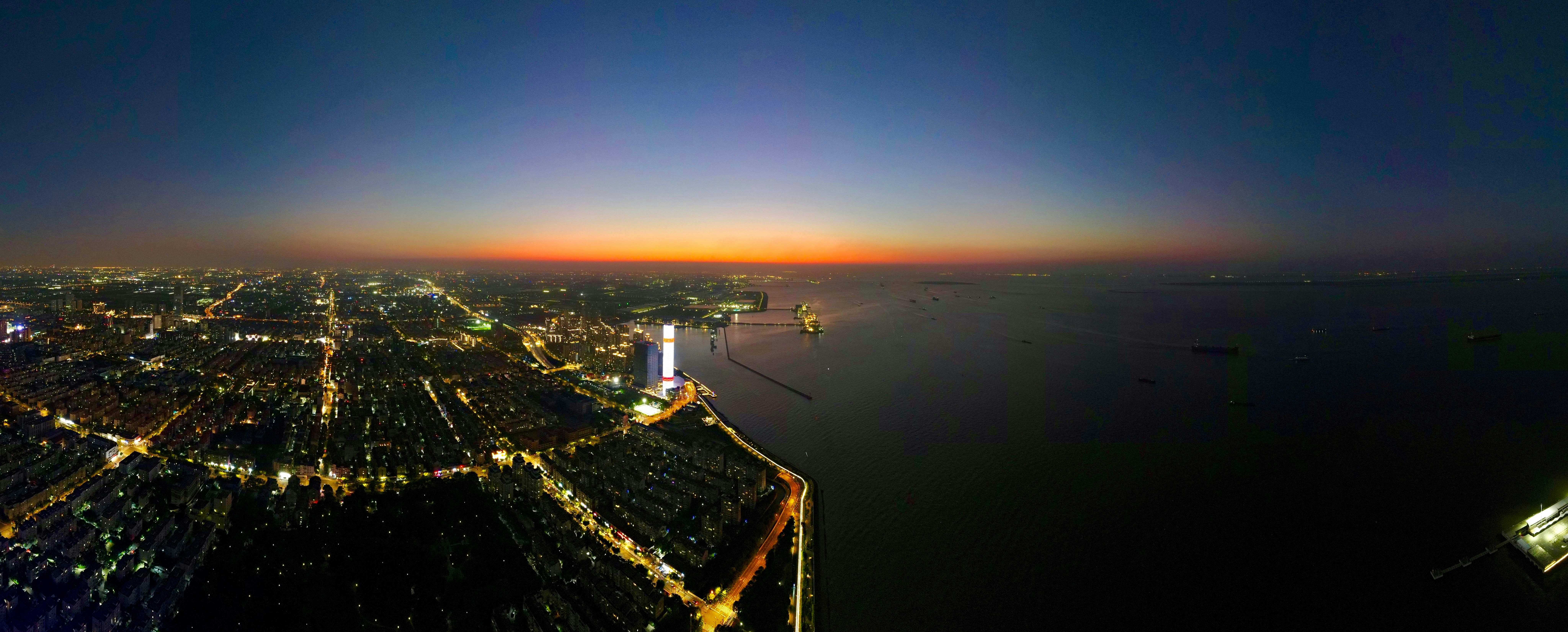 Nighttime city lights meet the ocean at dusk.