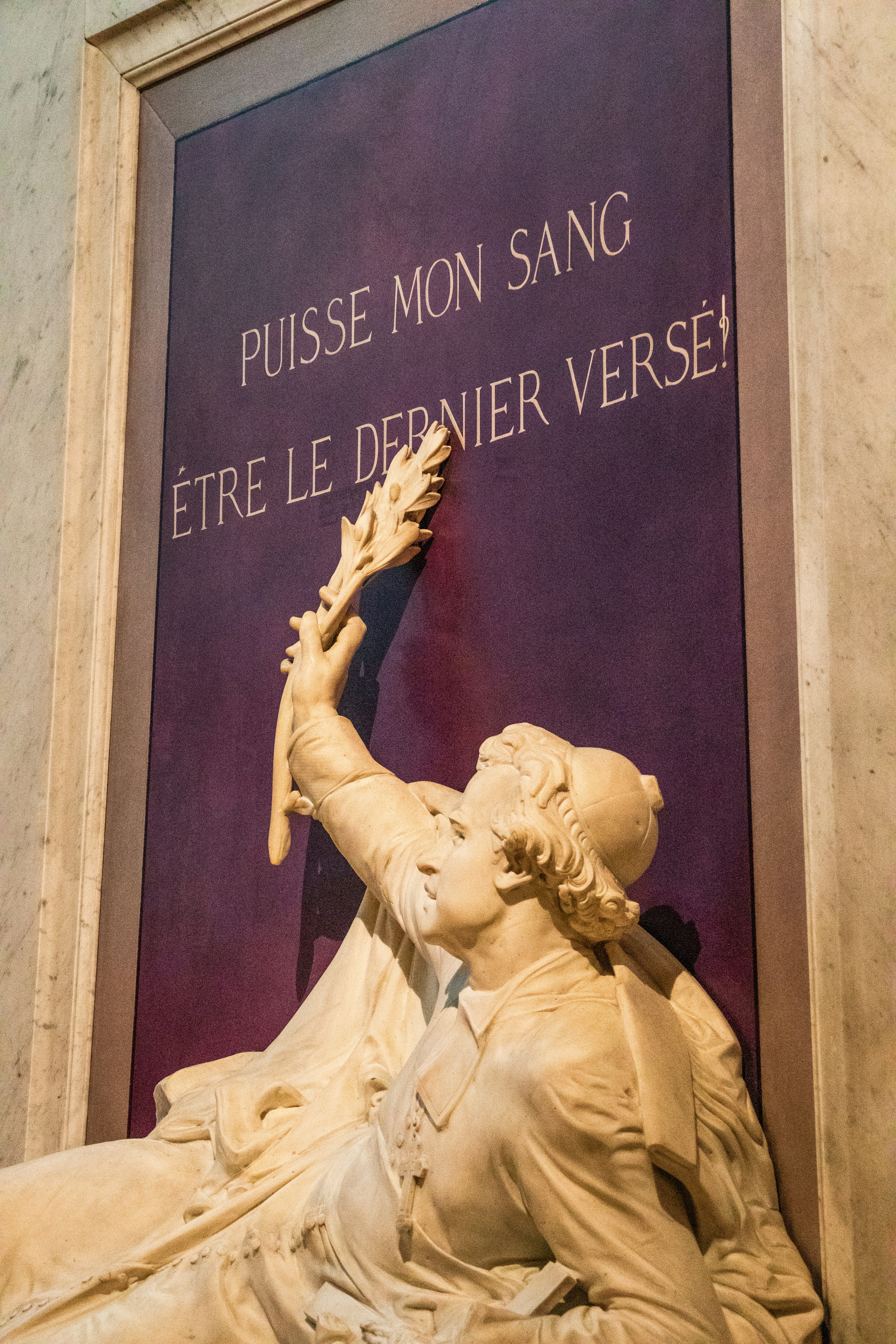 Sculpture en marbre avec inscription française sur un mur.