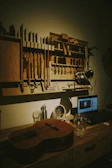 A workshop with tools, a guitar, and a laptop.