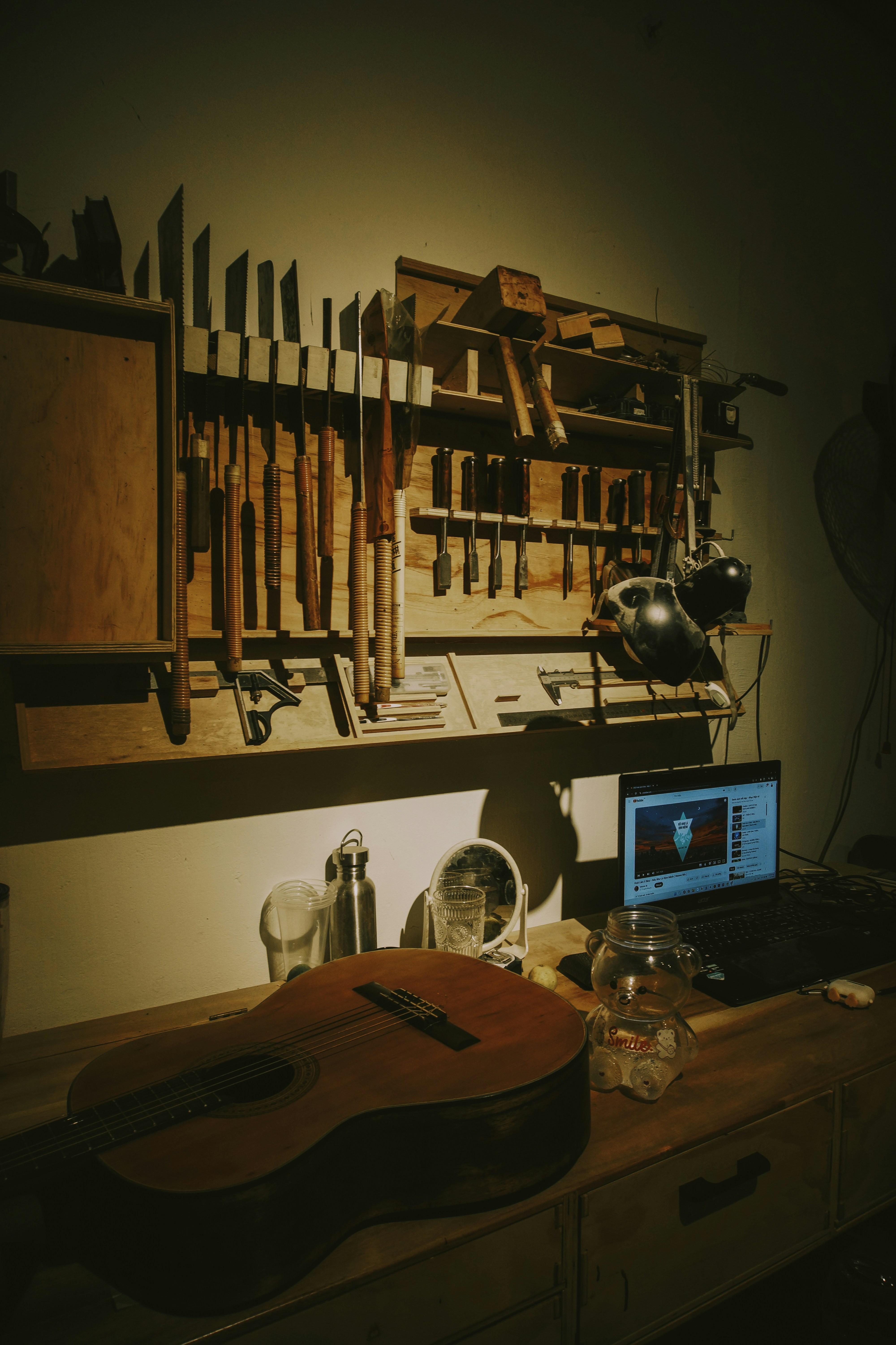 A workshop with tools, a guitar, and a laptop.