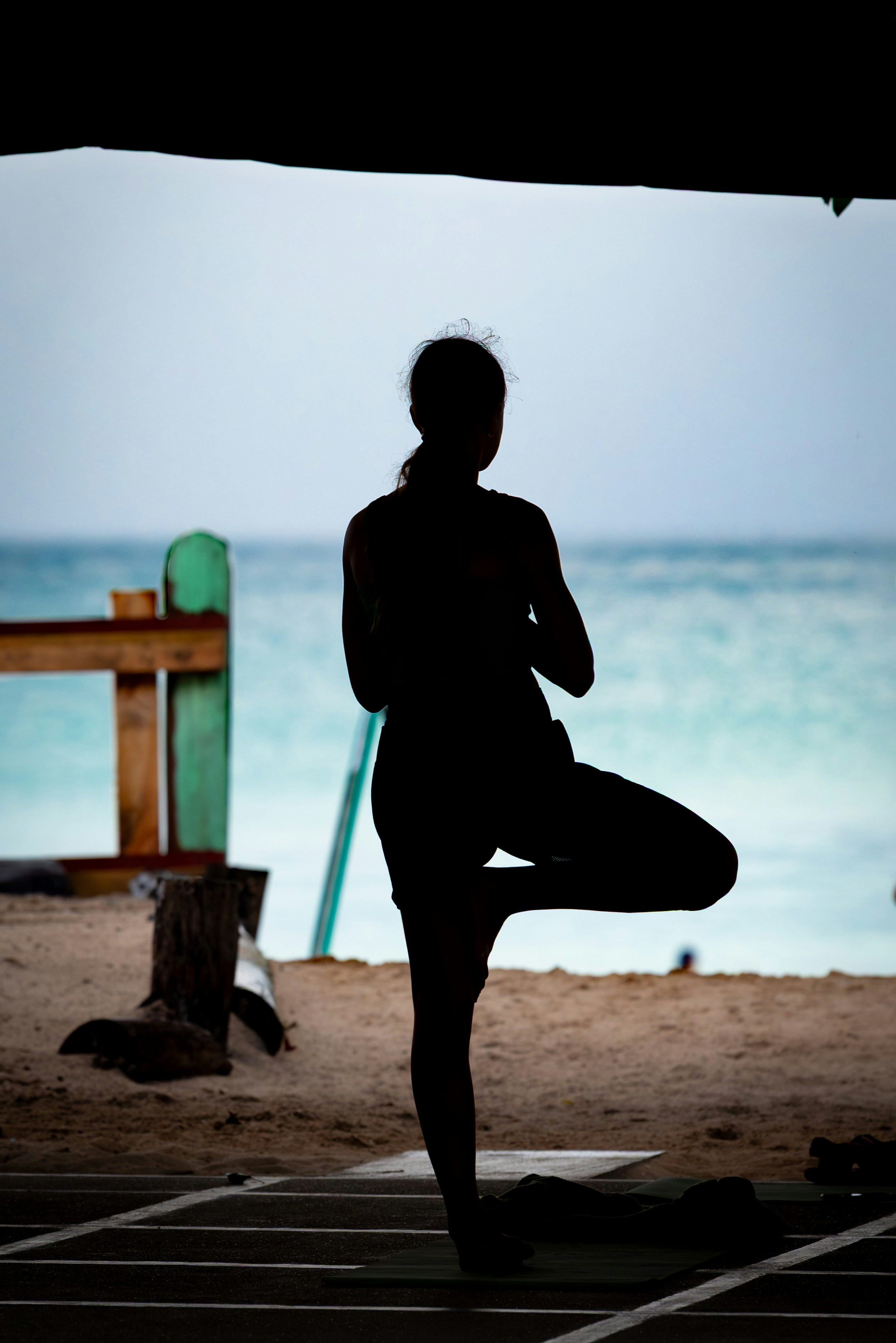Silhouette of a woman doing yoga by the ocean.
