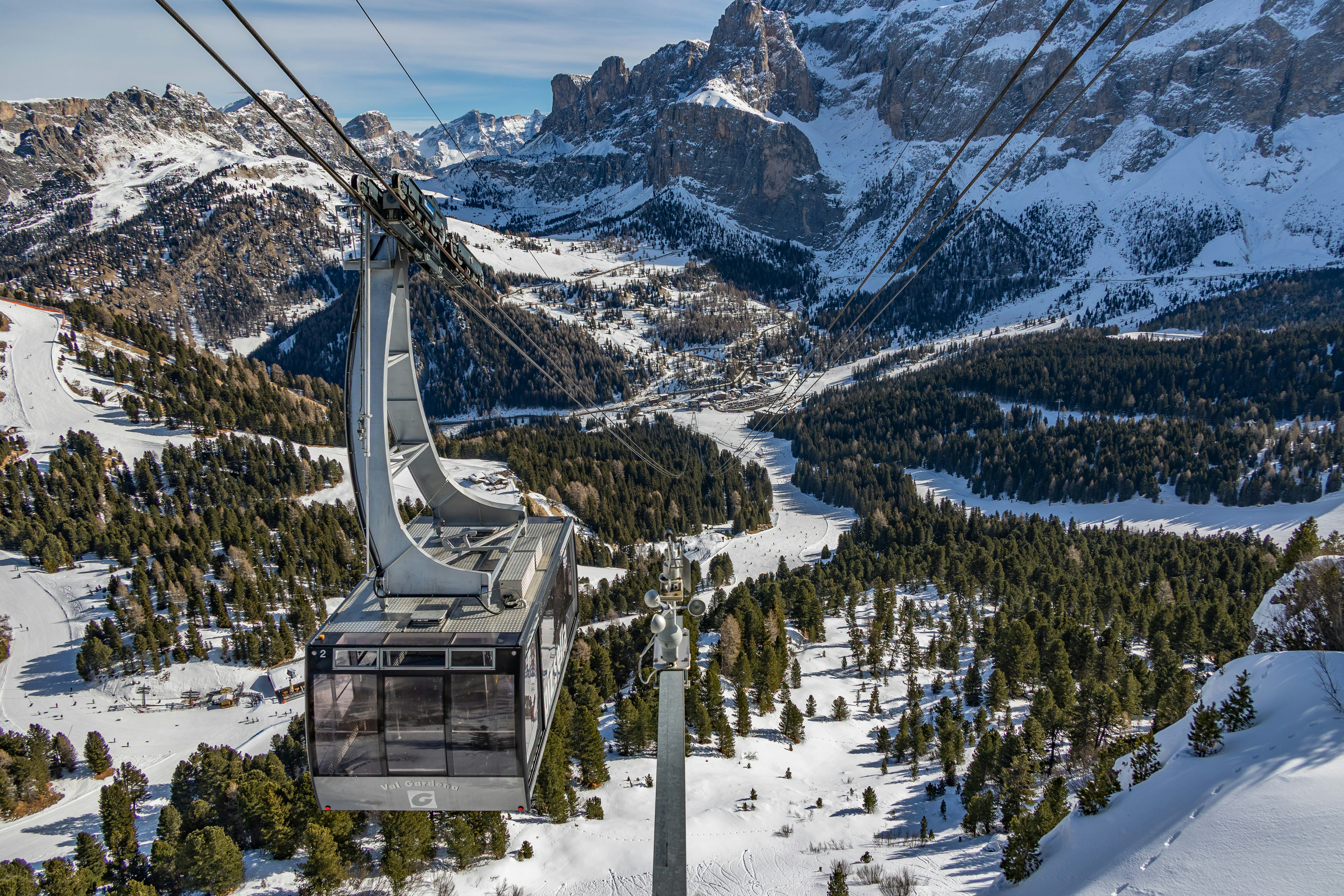 Una cabinovia sale sopra le montagne innevate.