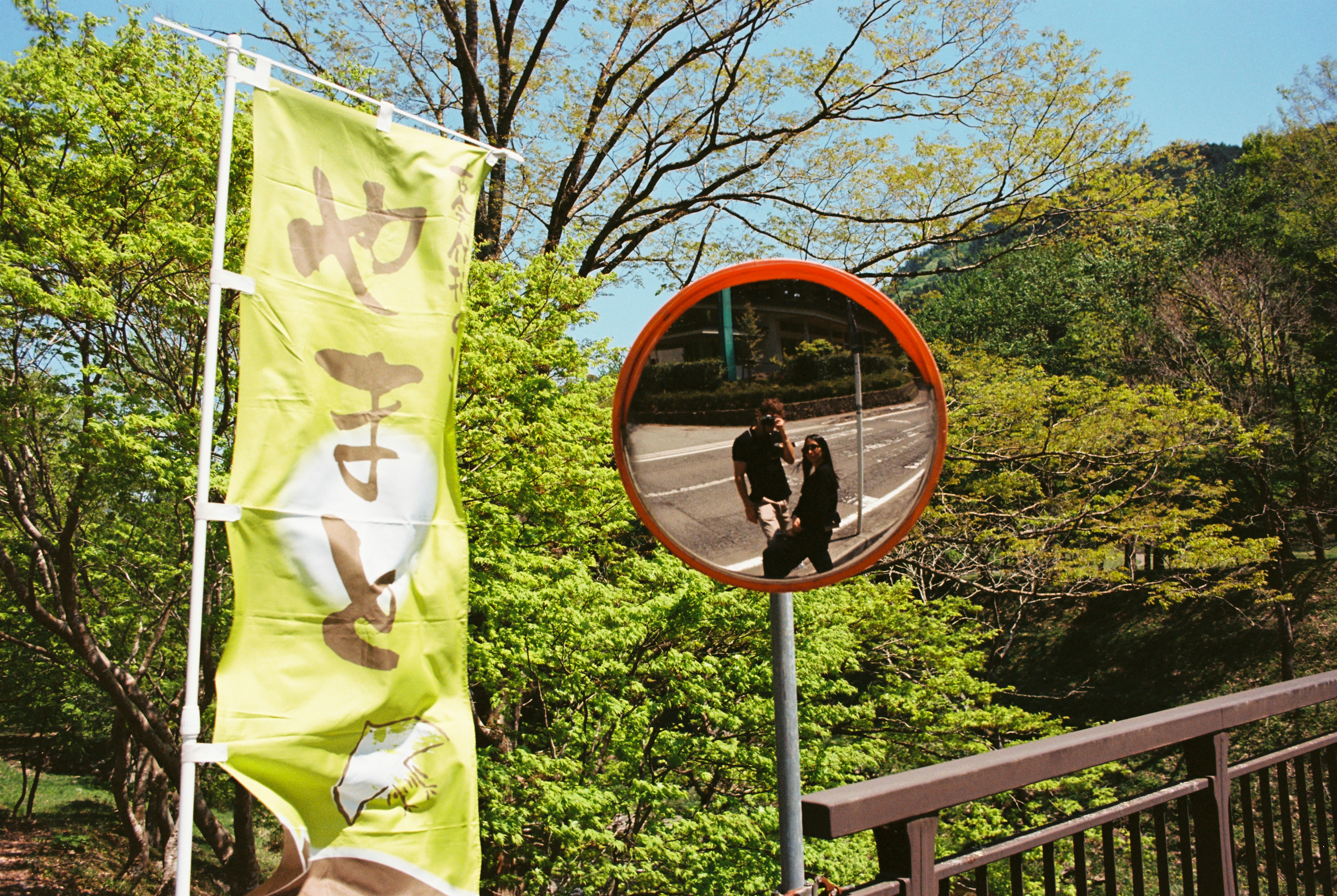 A round mirror reflects two people walking.