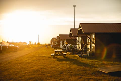 A row of wooden cabins in a grassy field at sunset