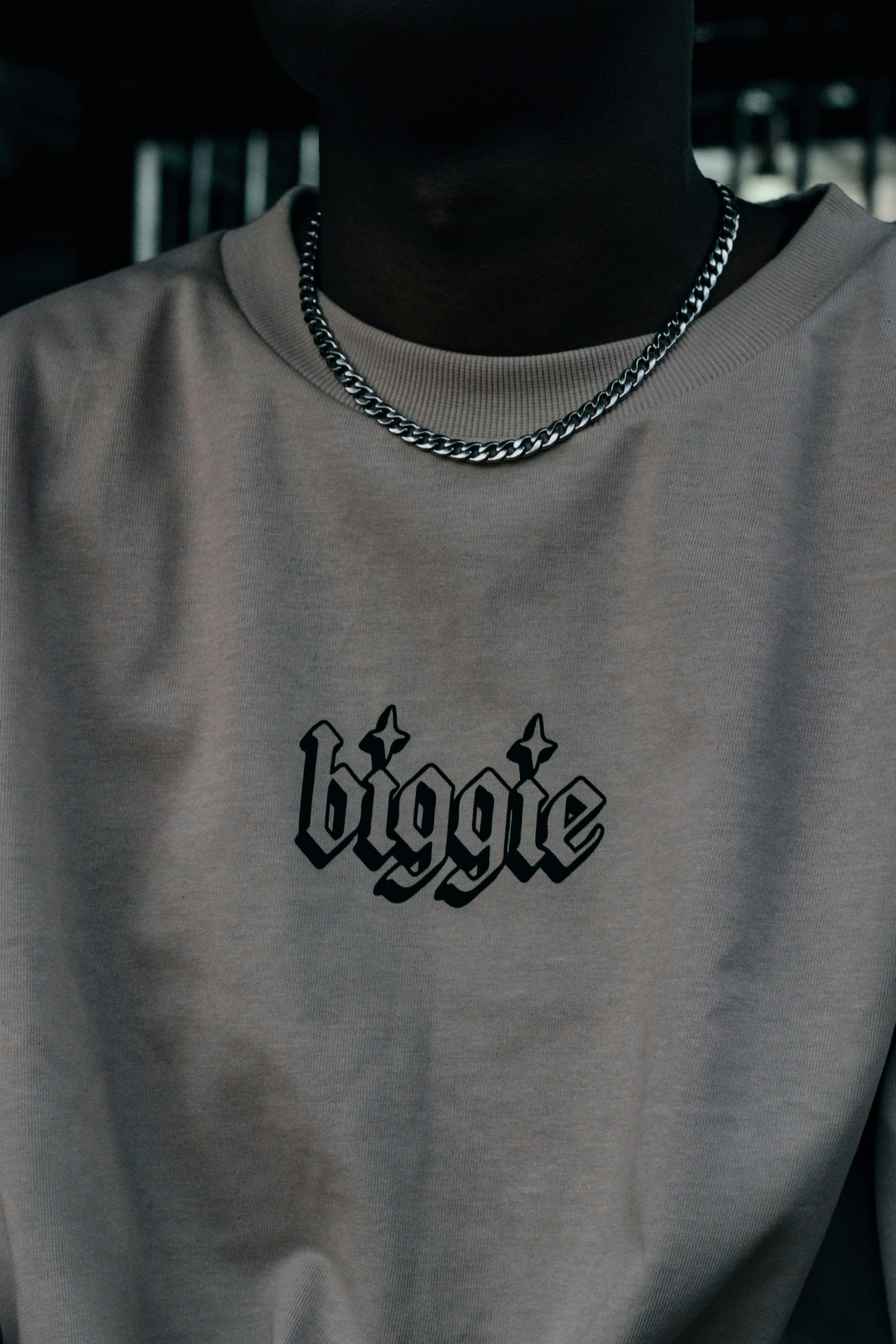 A person wears a "biggie" shirt and a chain.