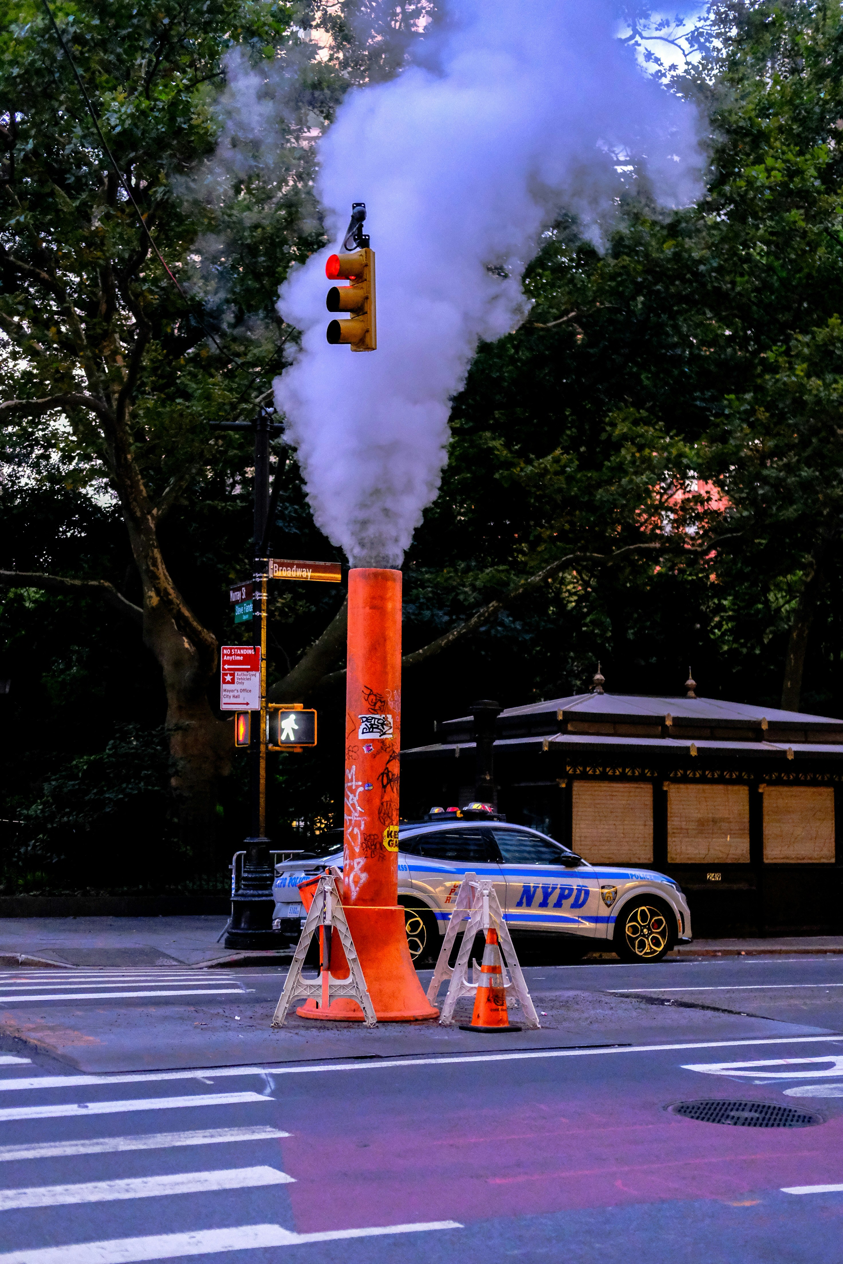 Steam rises from a pipe near a traffic light.
