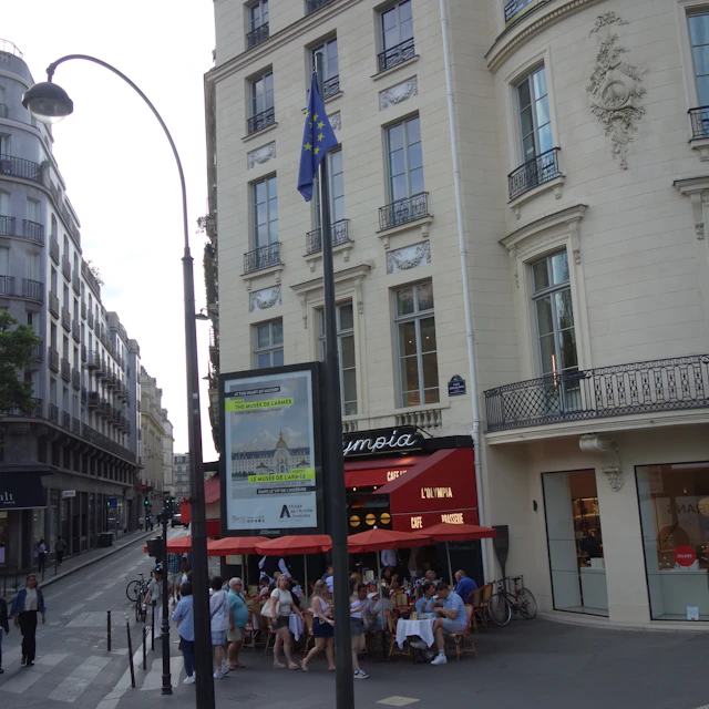 A Paris street with ground-floor shops below classic stone apartment buildings