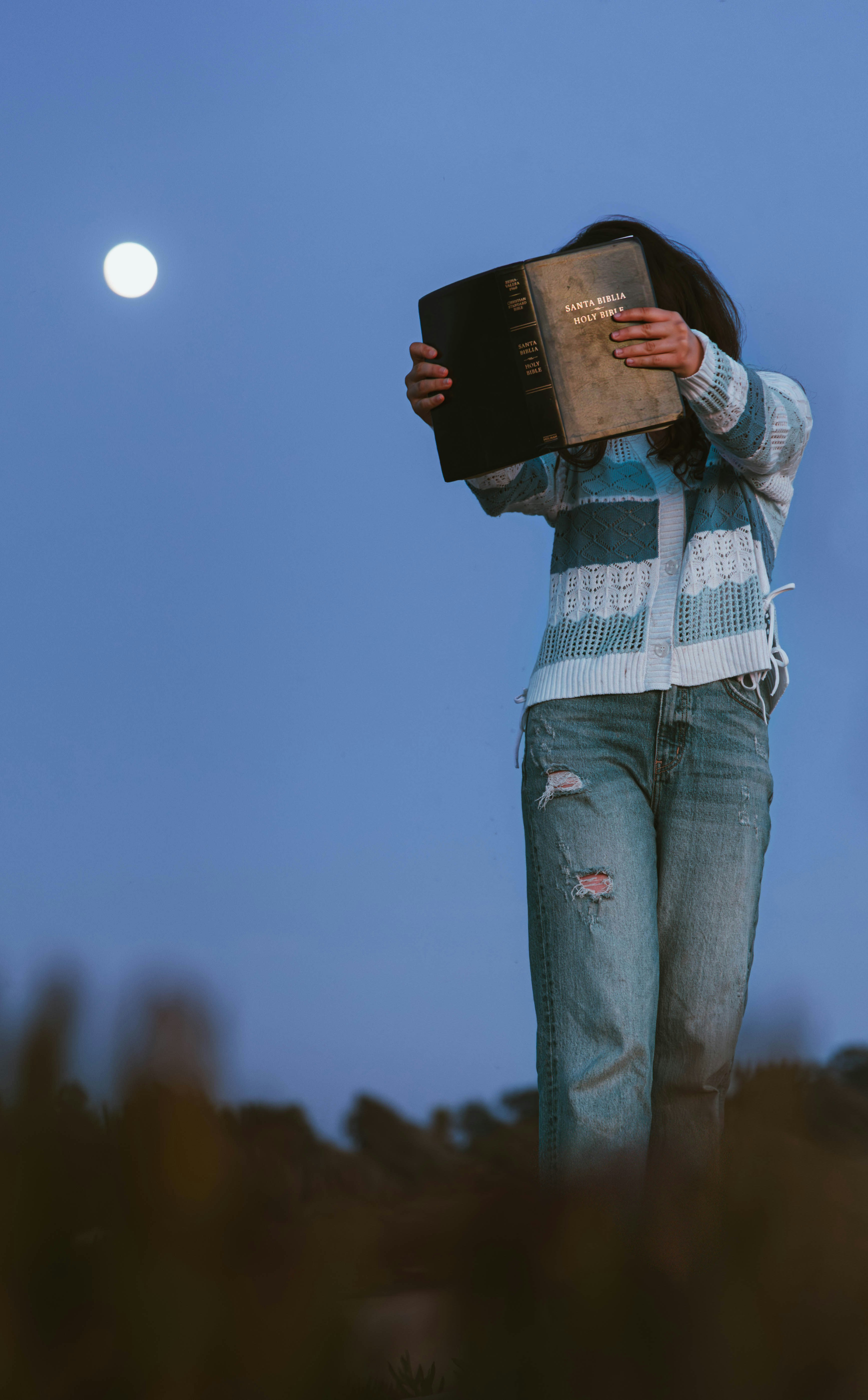 A person reads a book under the moonlight.