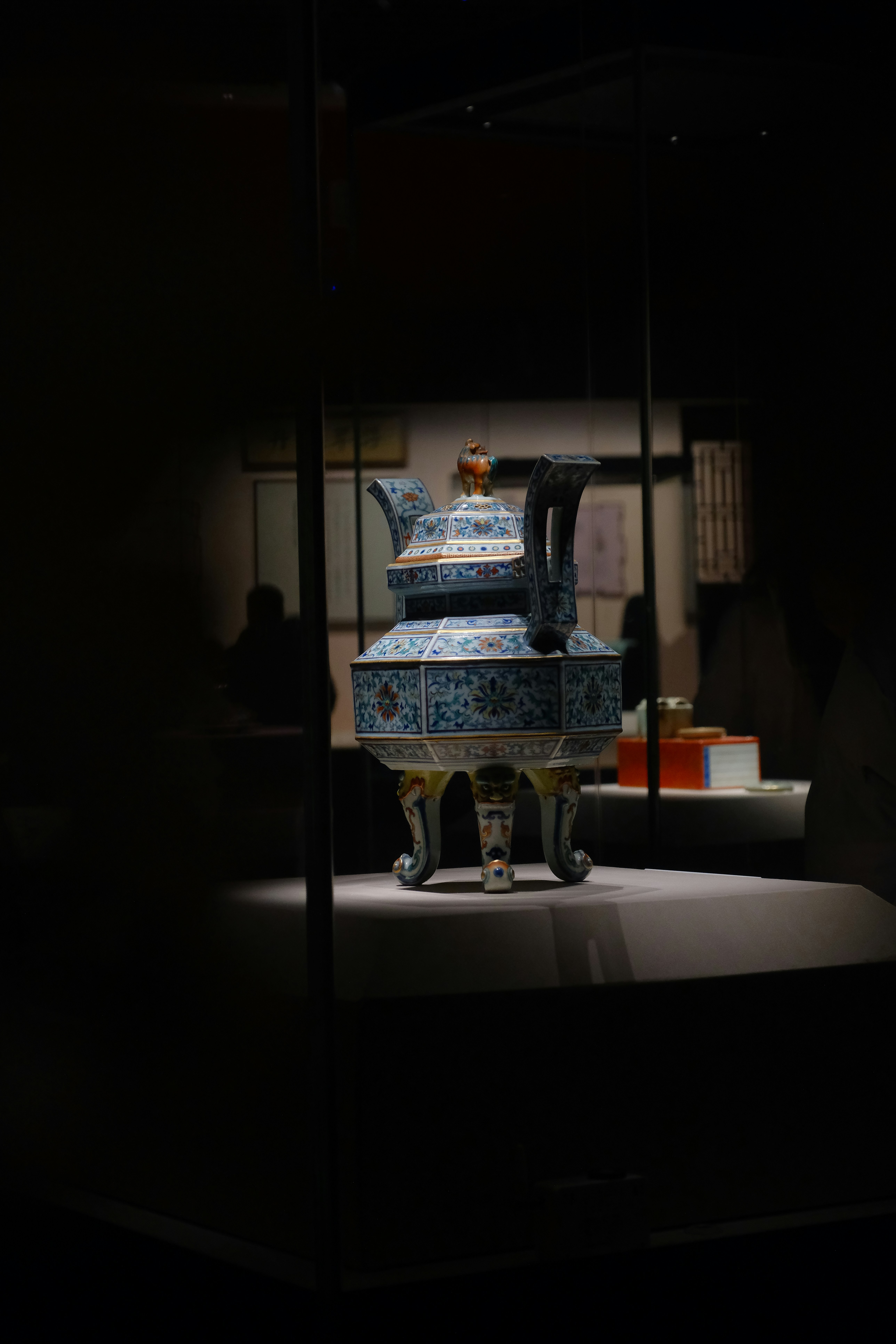 Antique chinese teapot is showcased in a glass case.