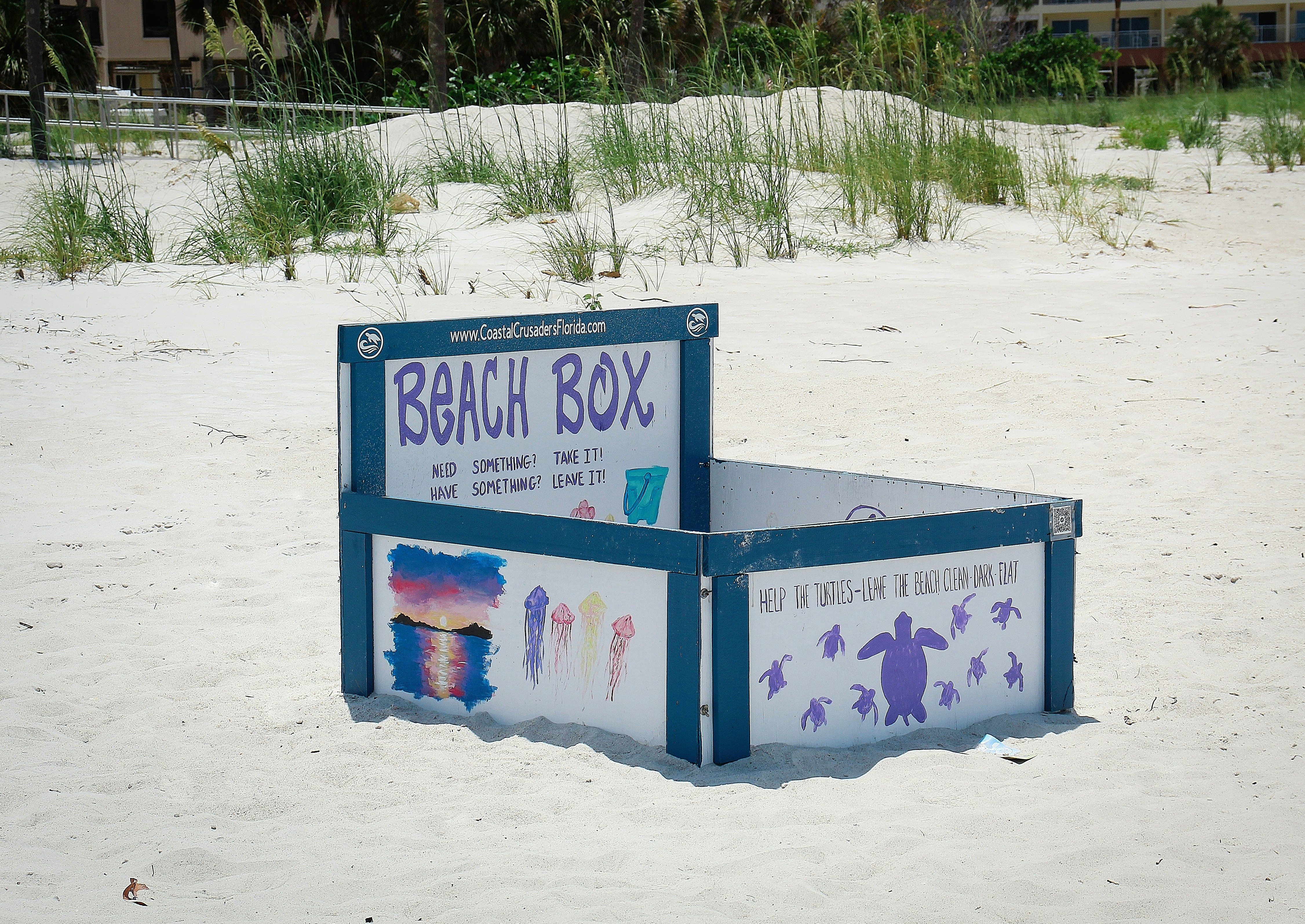 A beach box sits on a sandy beach.