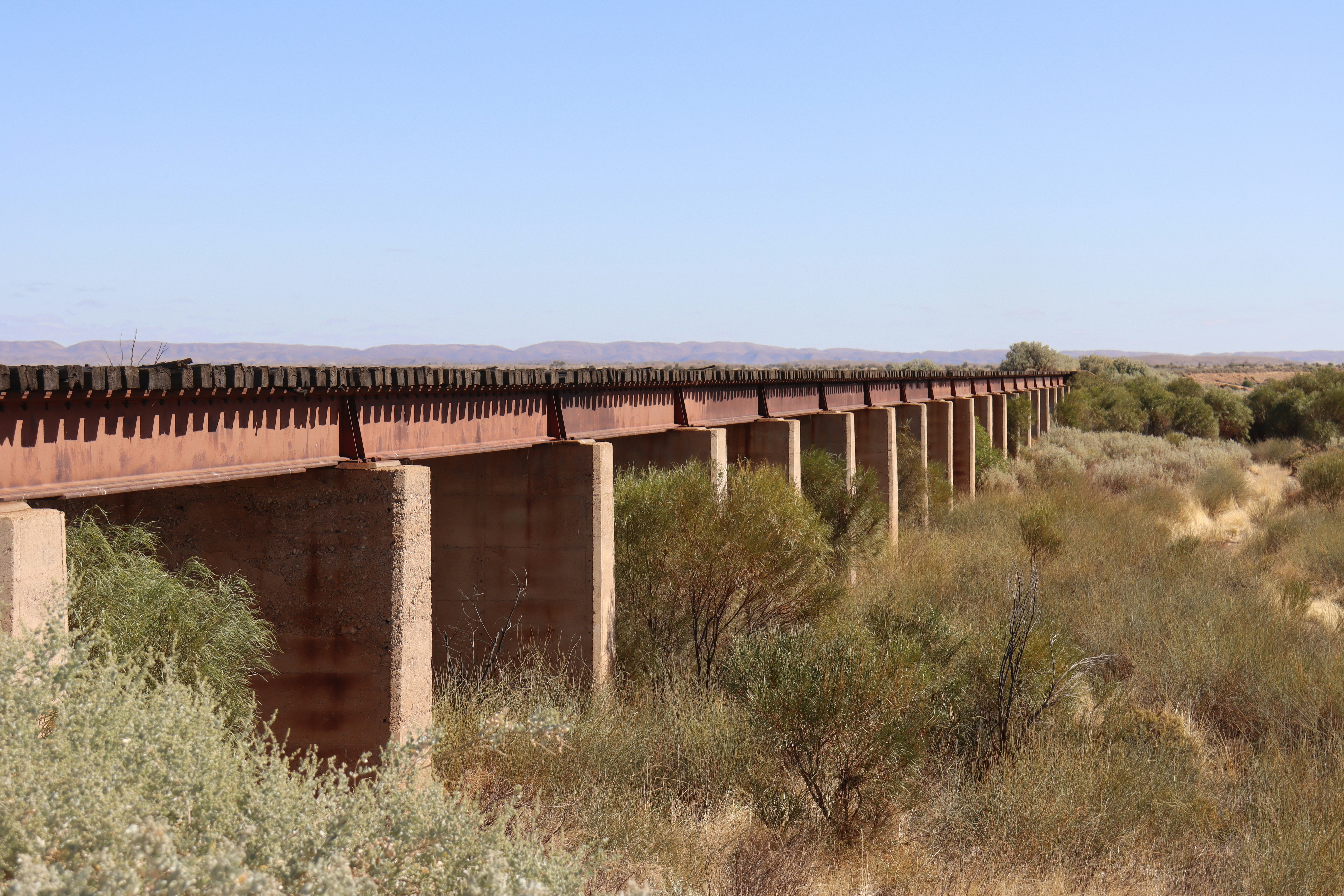 A train bridge spans across dry landscape.