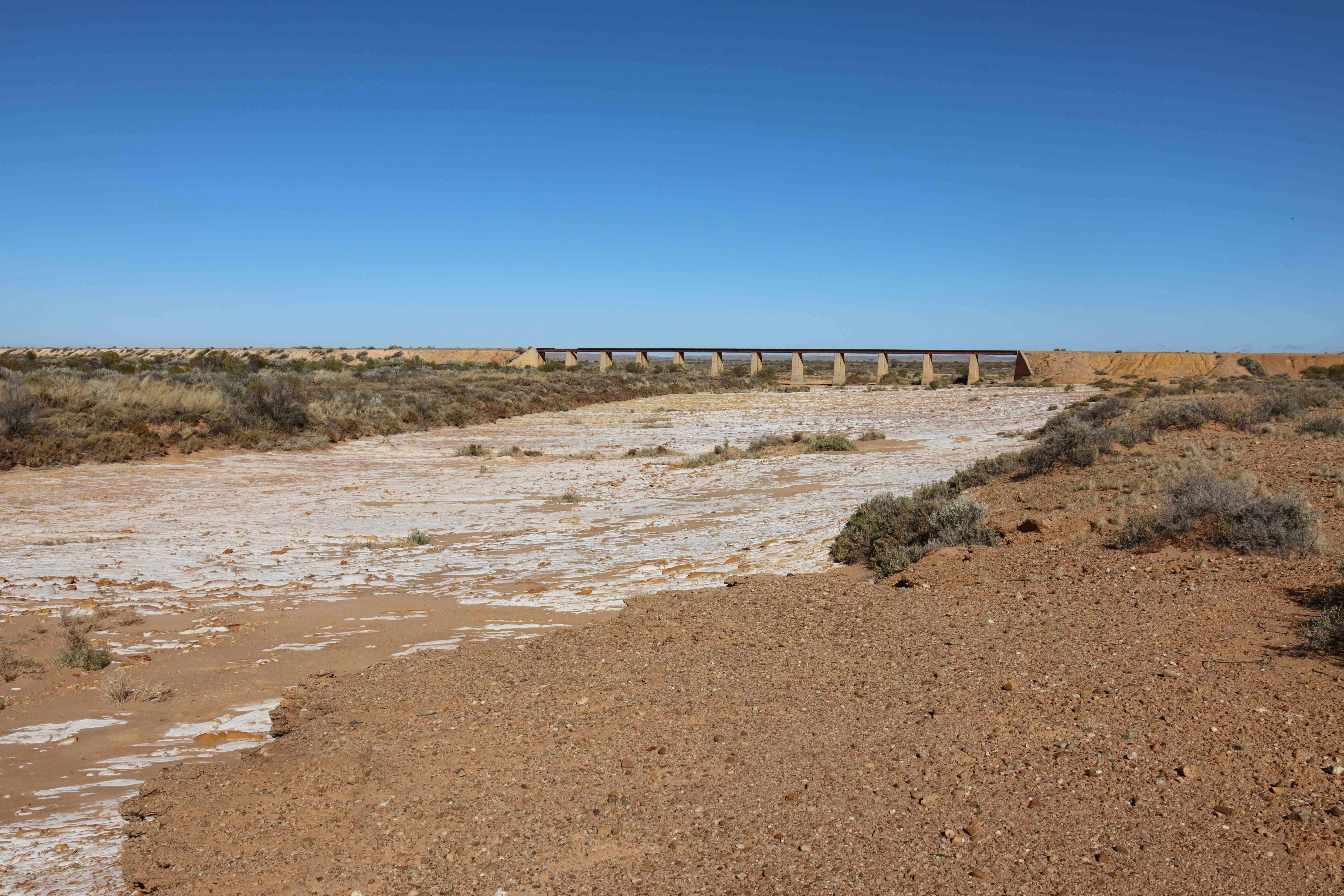 Dried-up riverbed in a dry, open landscape.