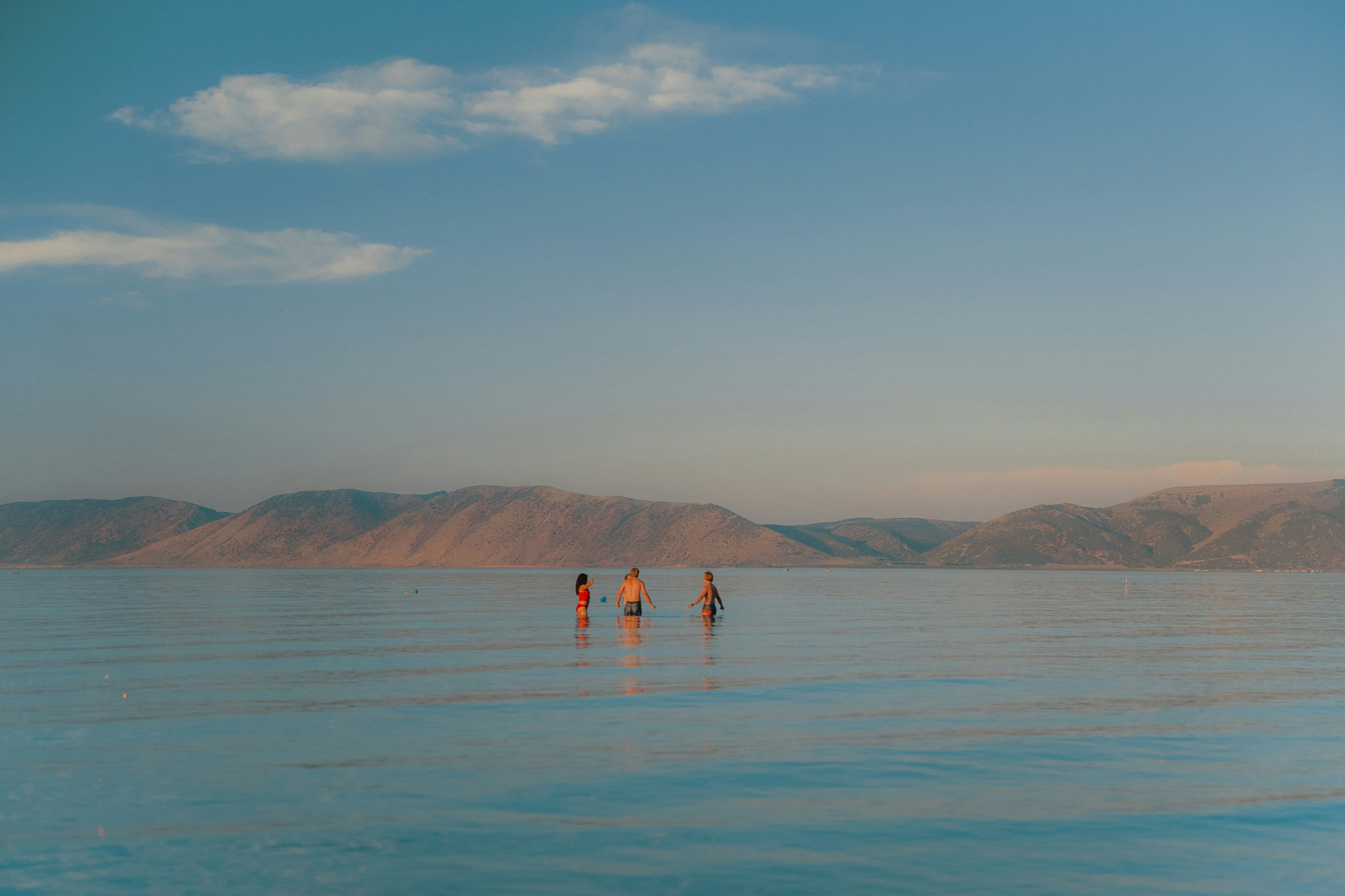 People are wading in the water under a blue sky.