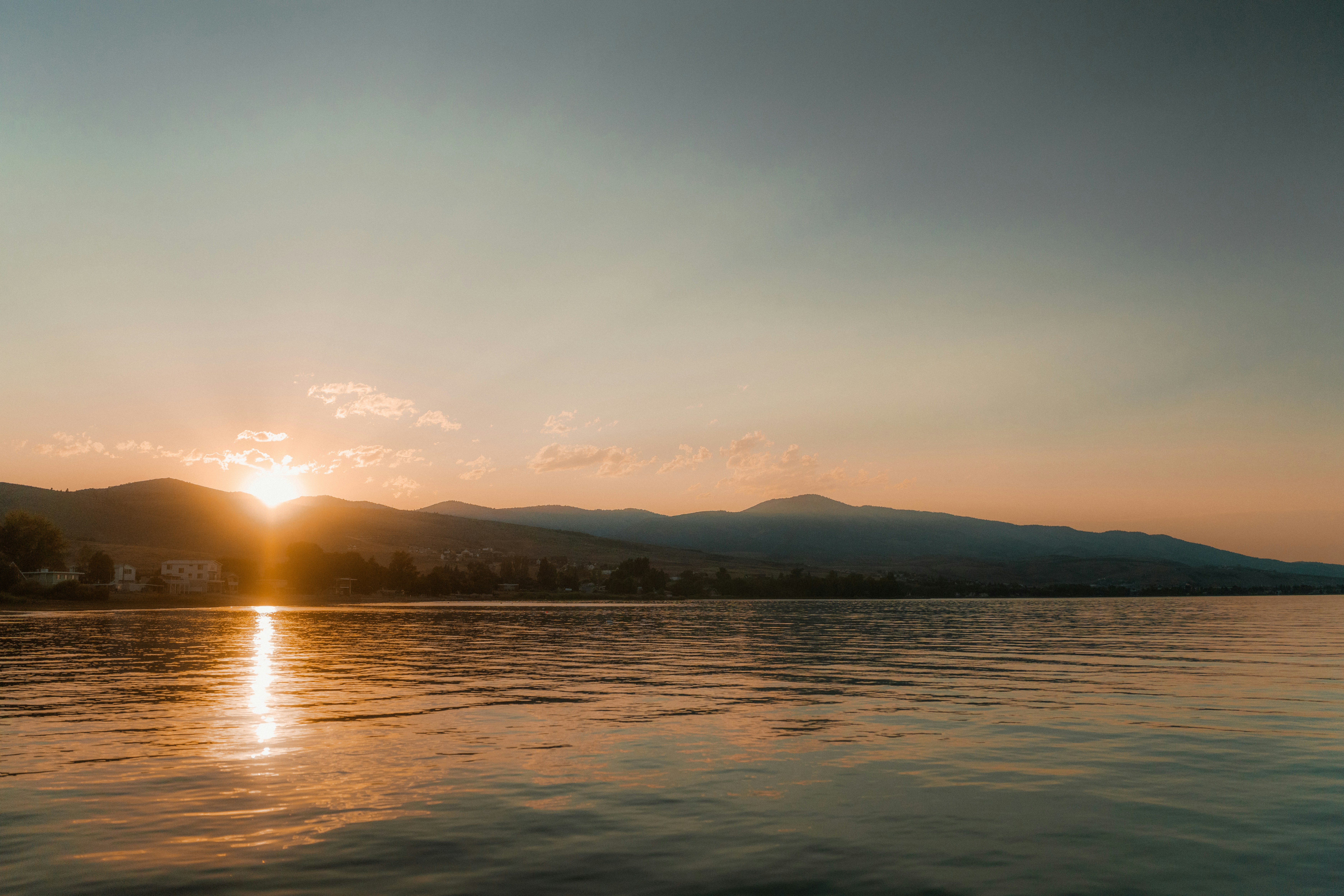 Sunrise over a calm lake and mountains.