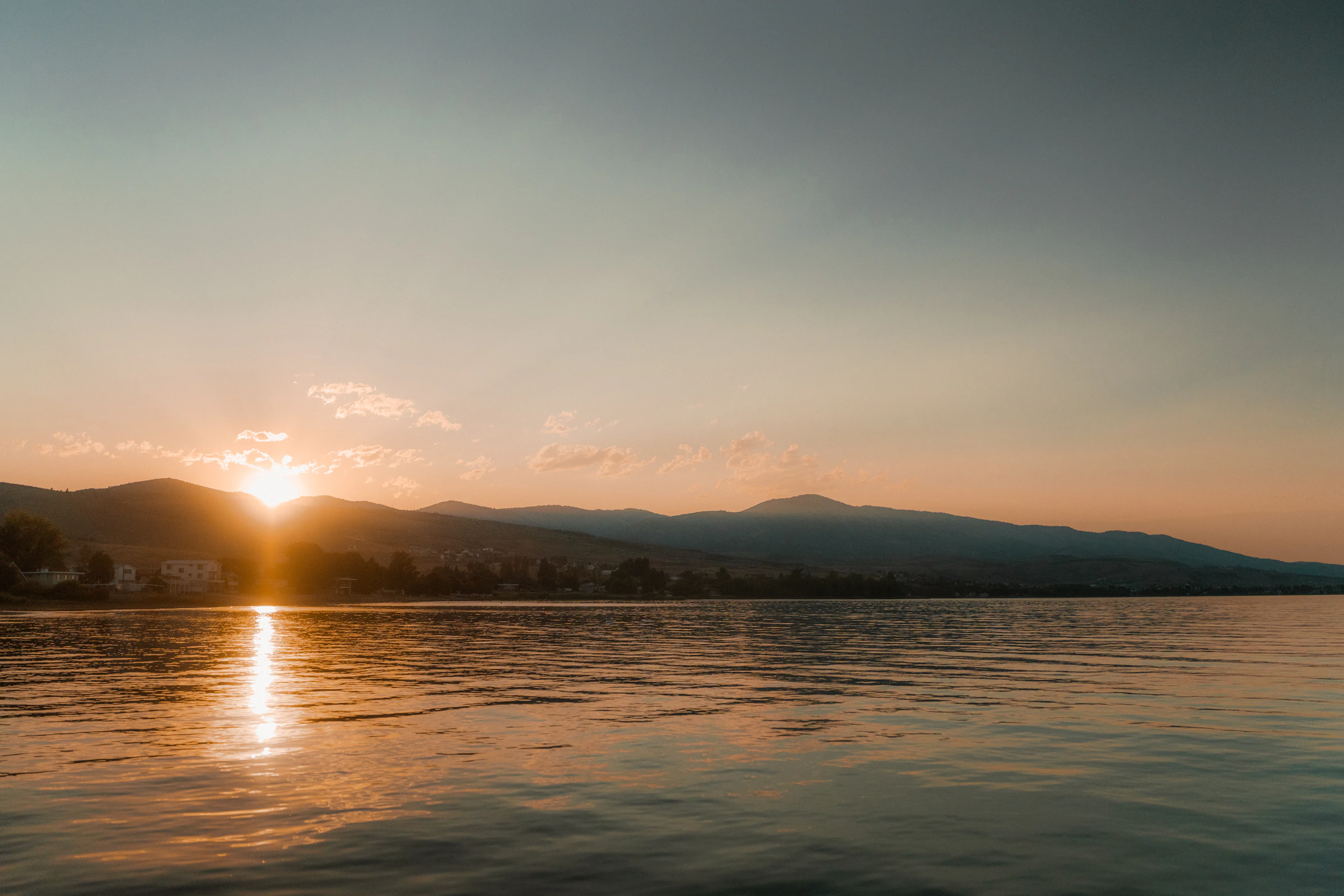 First light breaking over still, calm water at dawn