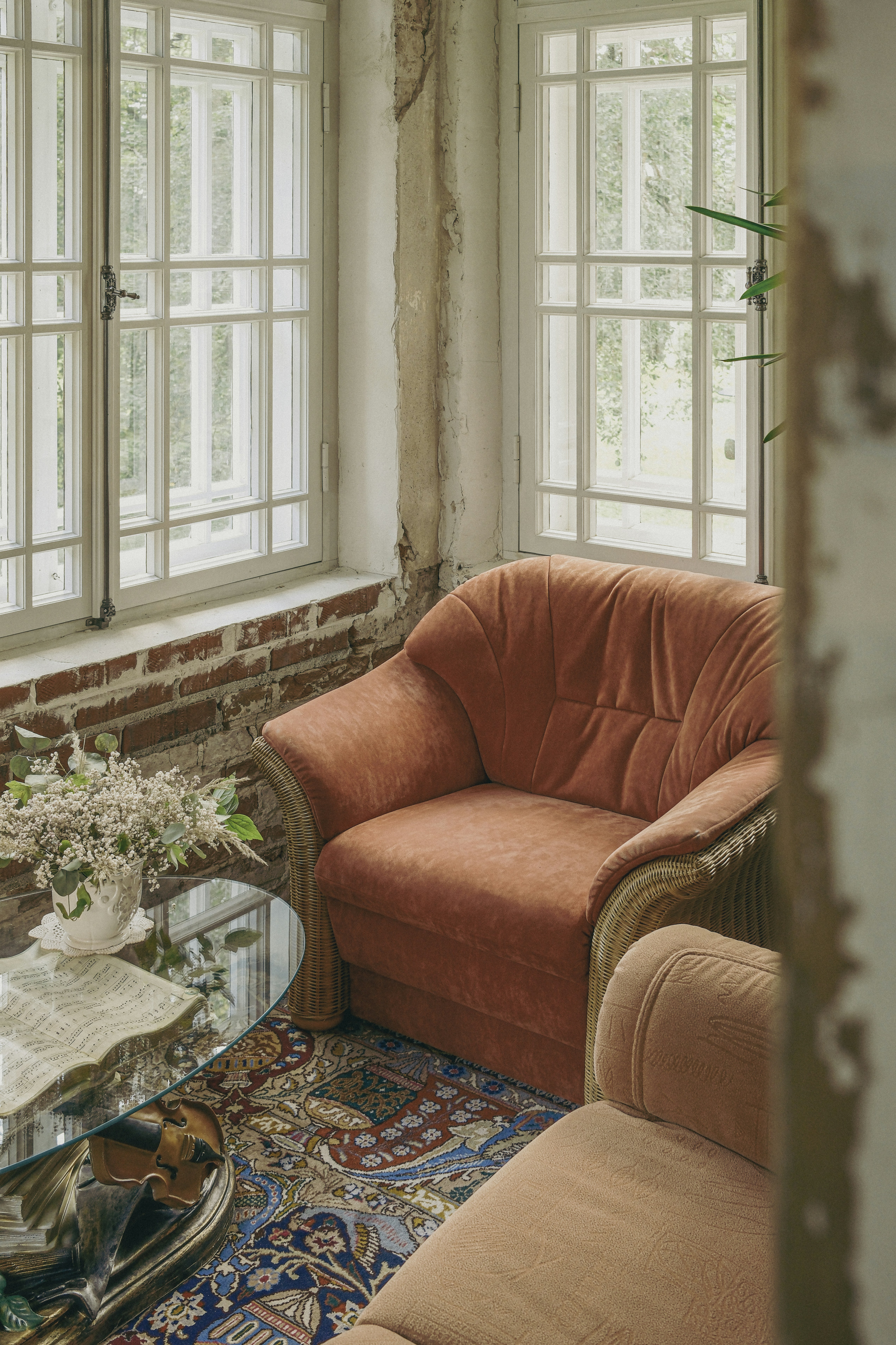 Cozy armchair sits next to windows in a rustic room.