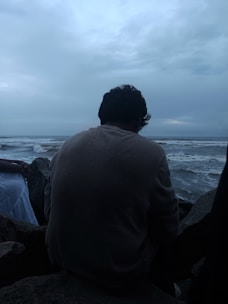 Man contemplates the ocean under a stormy sky.