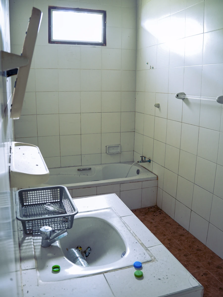 Salle de bain avant rénovation à Carvin, carrelage ancien et tuyauterie apparente