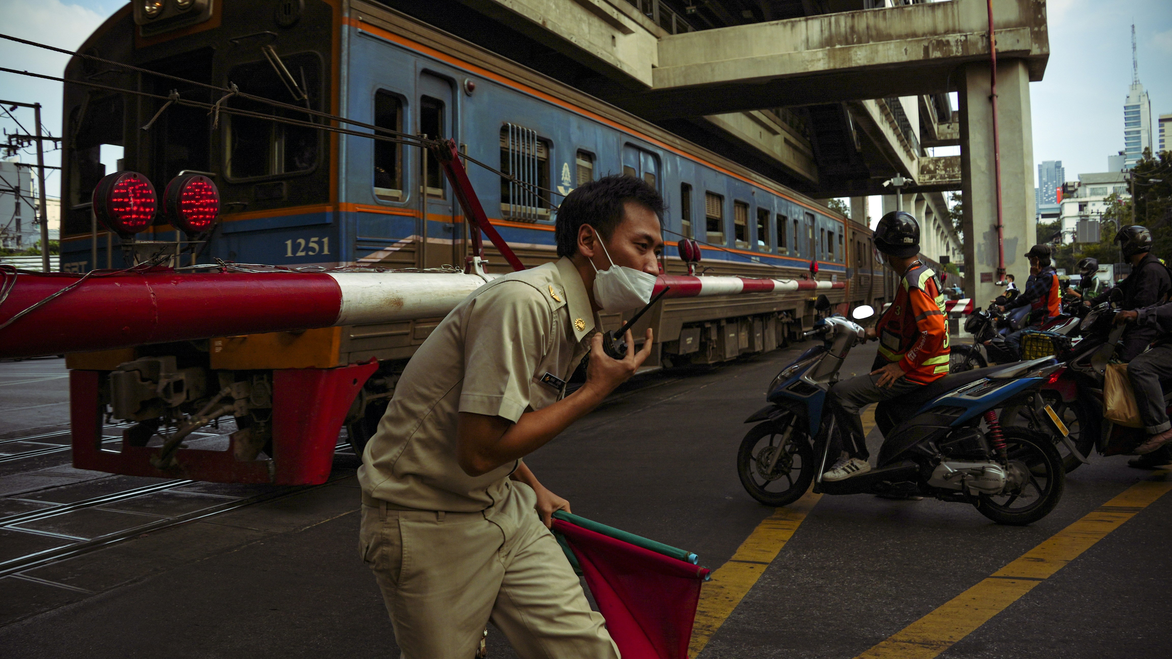 Ein Zug fährt vorbei, als ein Arbeiter eine Flagge hisst.