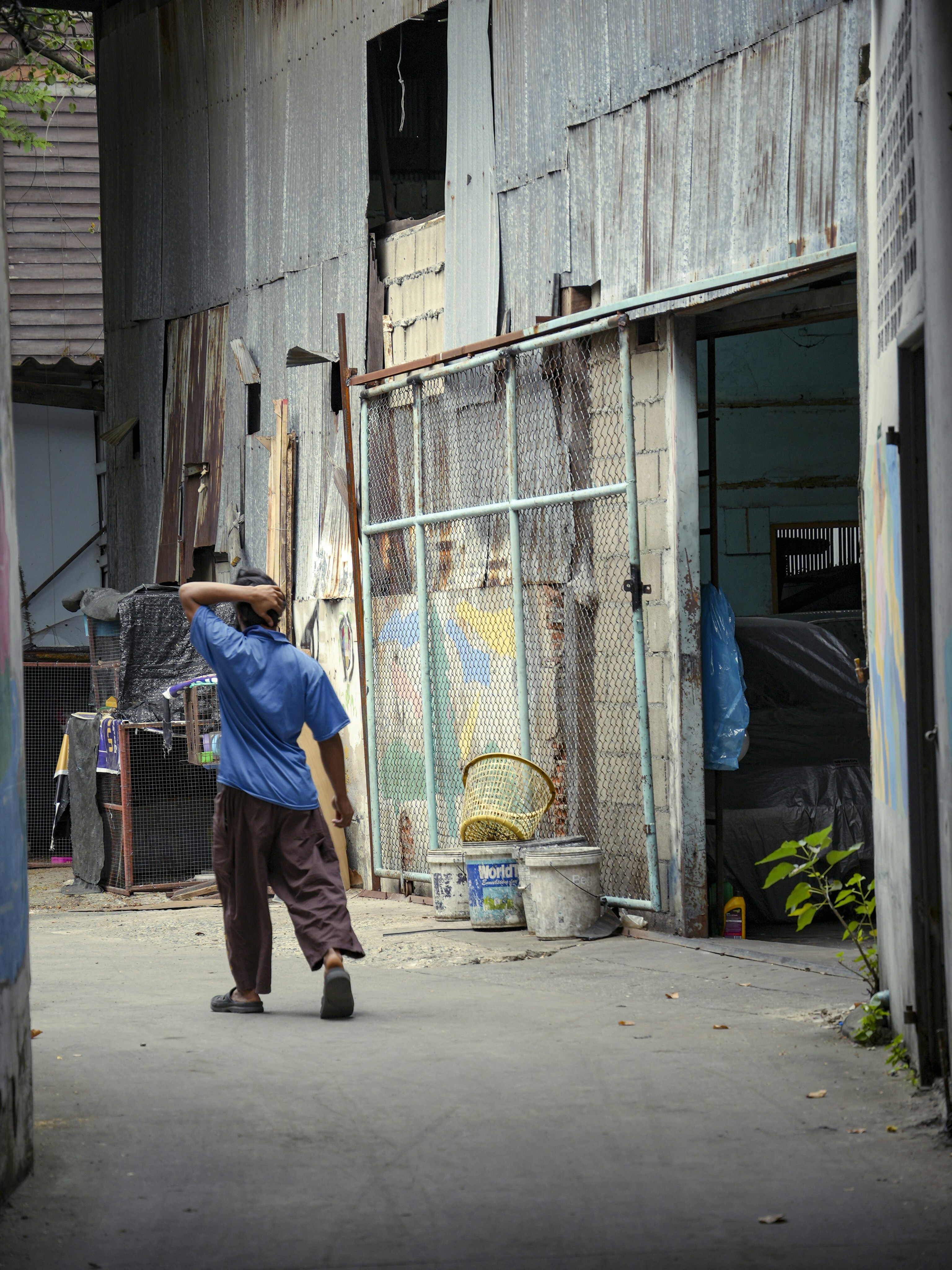 A man walks through a run-down alleyway.