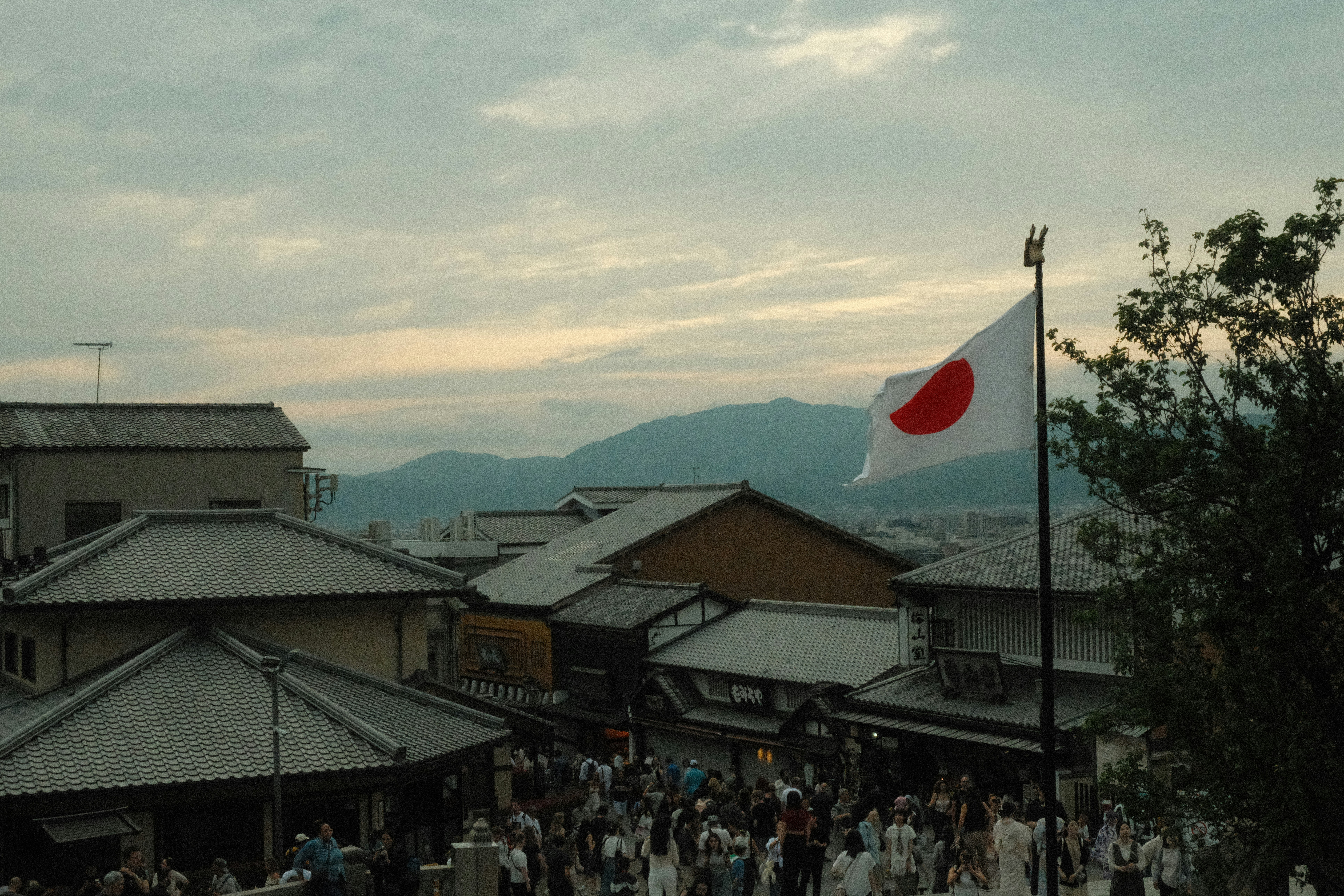 Japanese flag waves above a busy street scene.