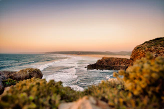 Ocean waves crash on the sandy shore at dusk