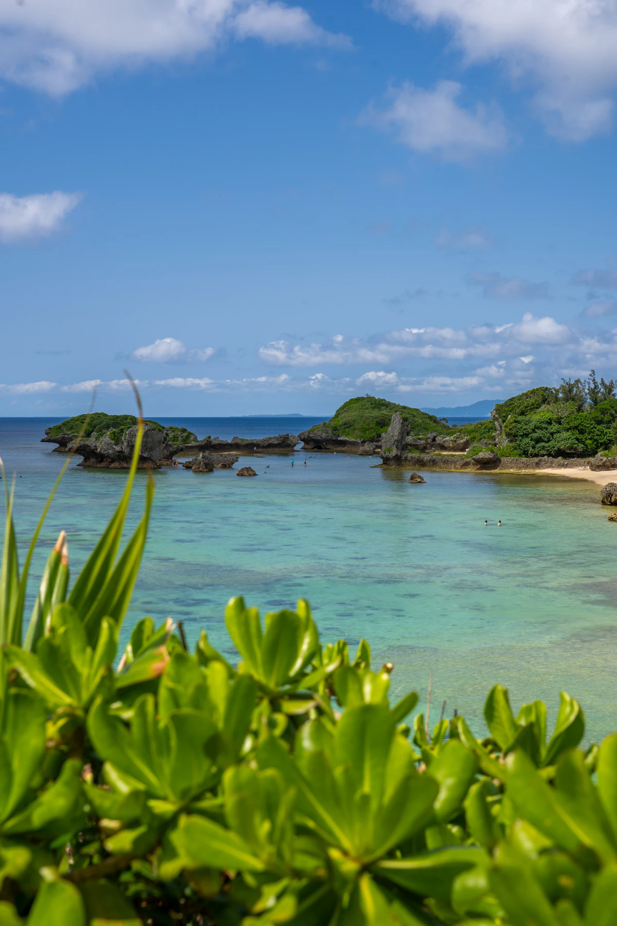 A turquoise ocean cove and sandy beach in Okinawa under a clear summer sky