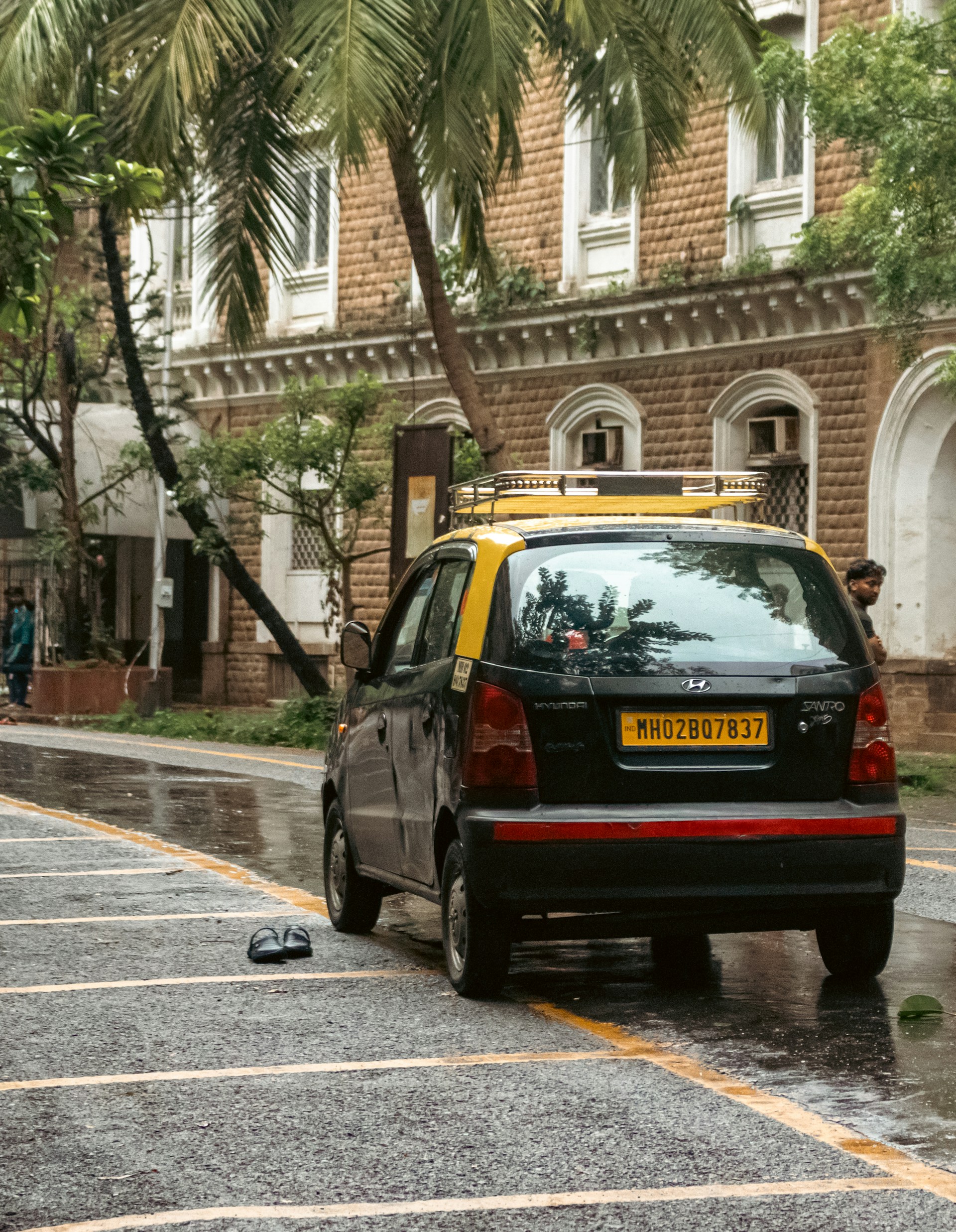 A taxi is parked on a wet street.