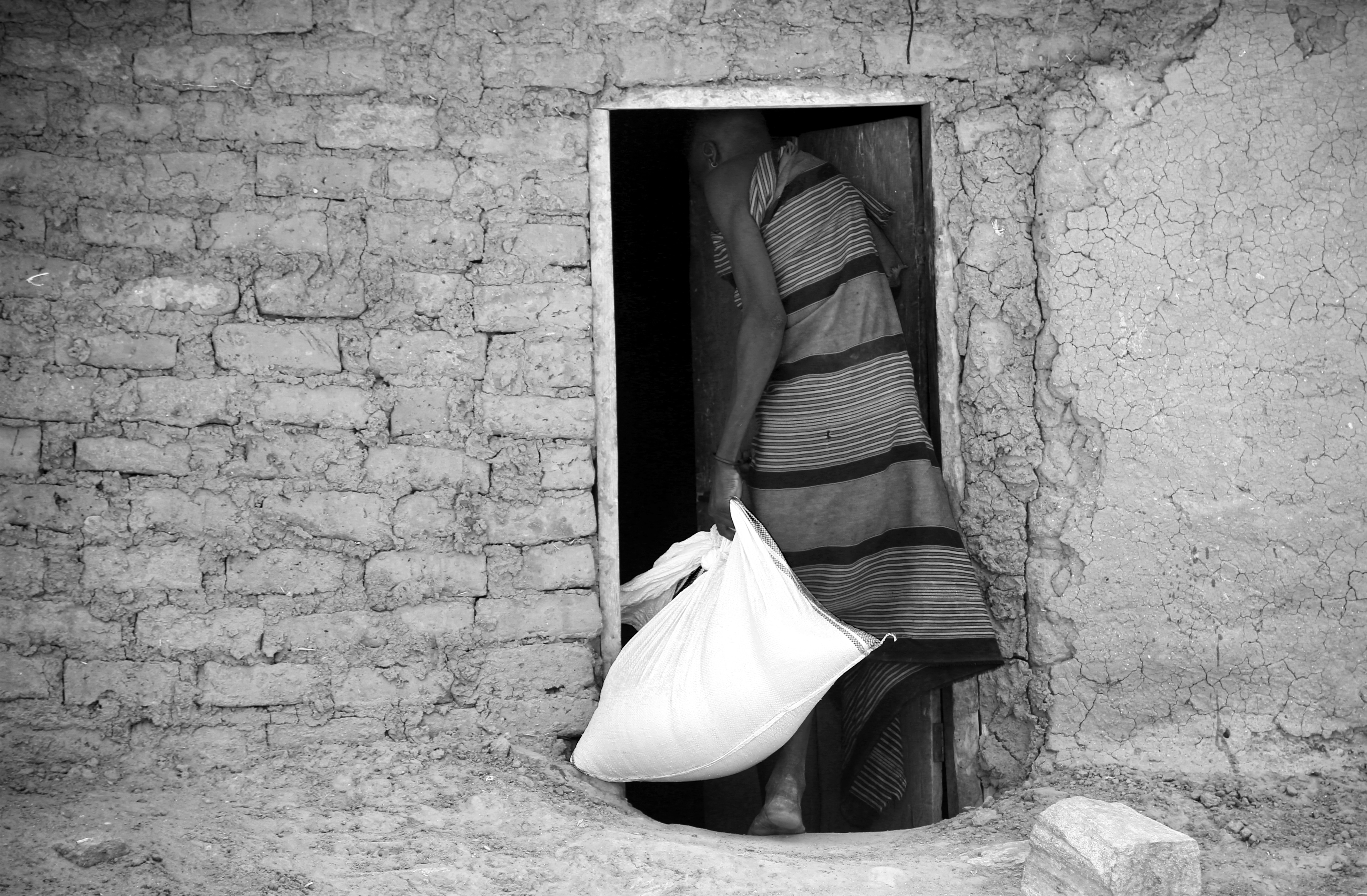 A person exits a doorway carrying a bag.