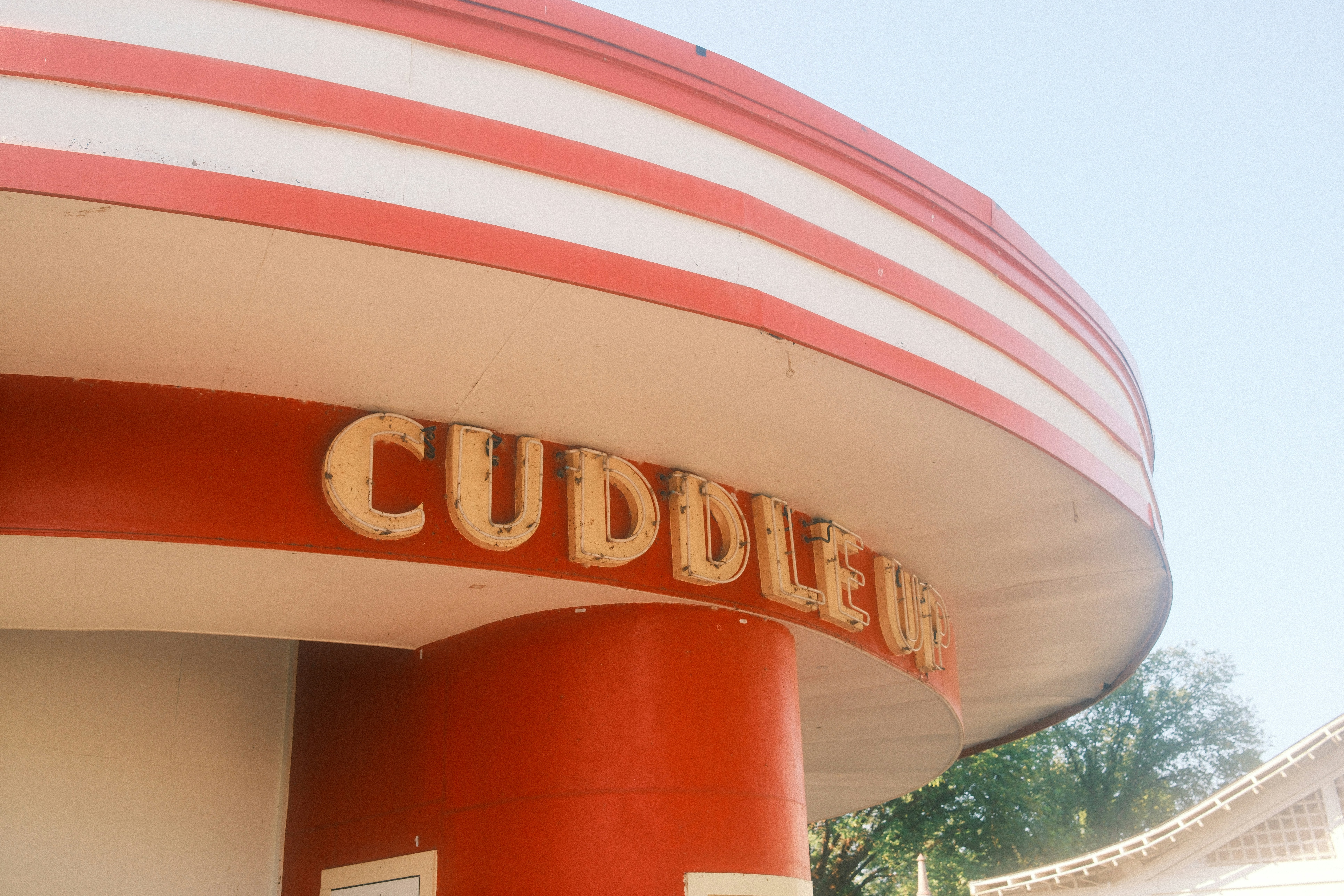 Cuddle inn's faded sign on a vintage building.