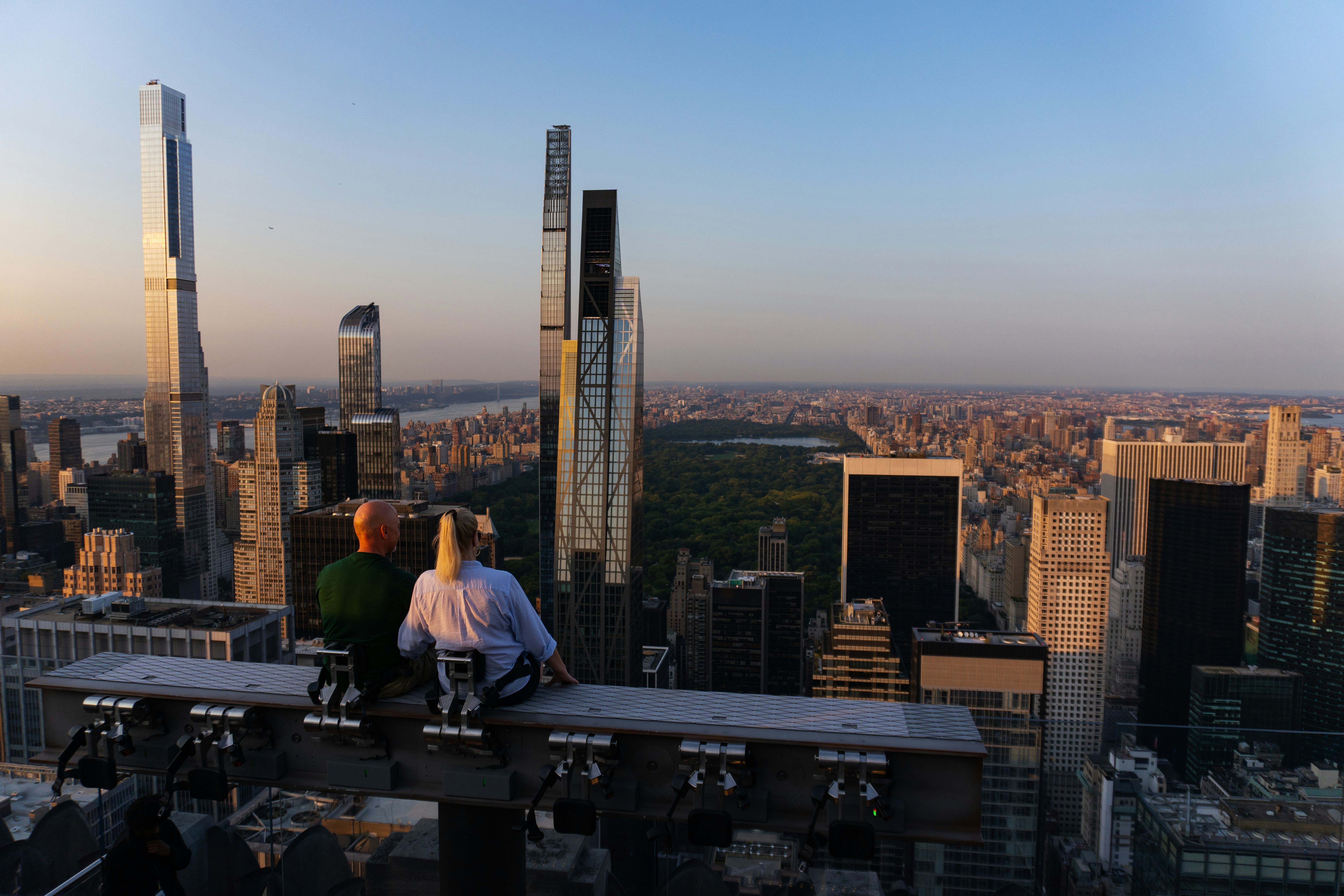 People admire the new york city skyline at sunset.