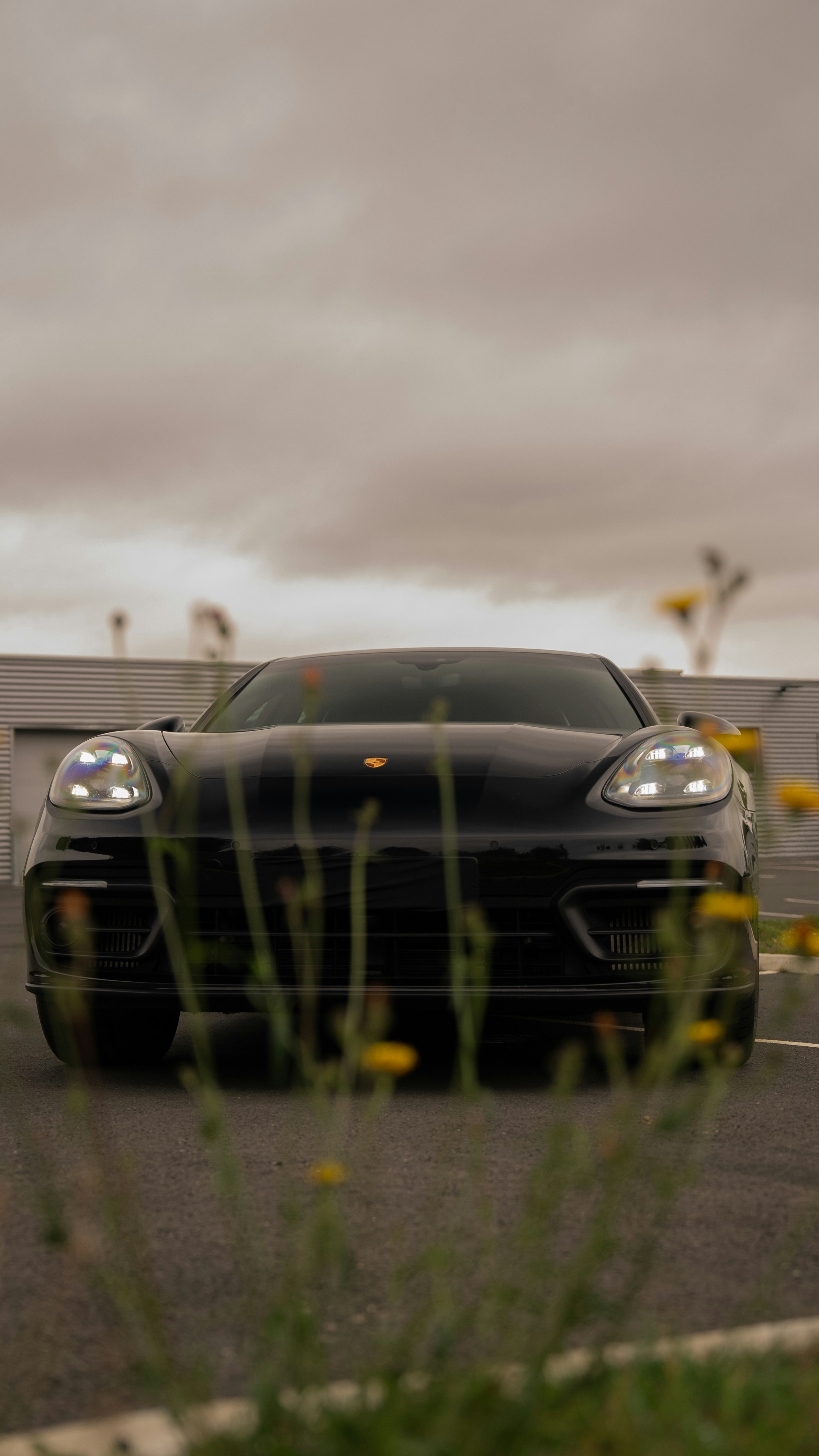 A black porsche sits in a parking lot.