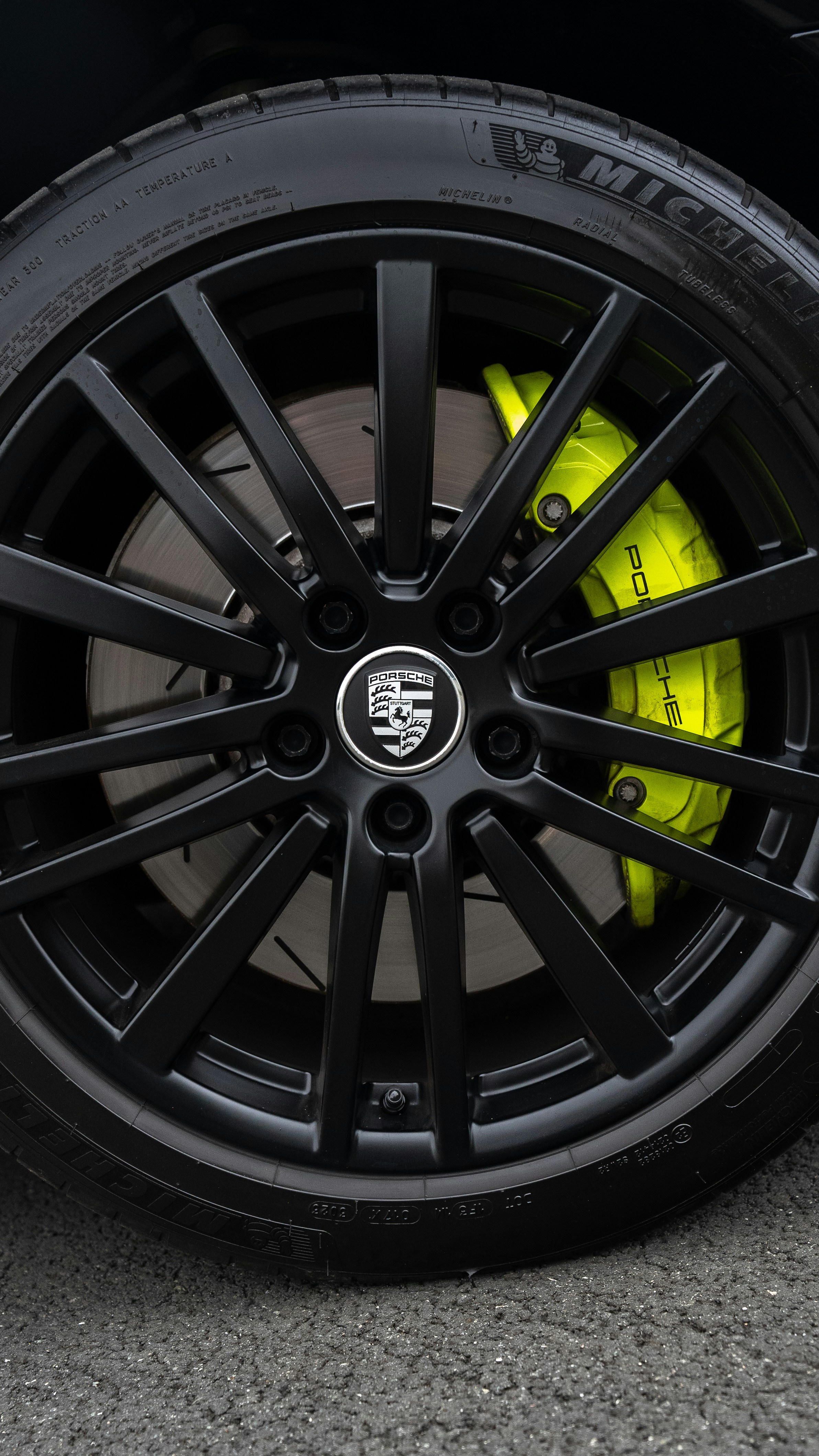 Black porsche wheel with lime green brake caliper.