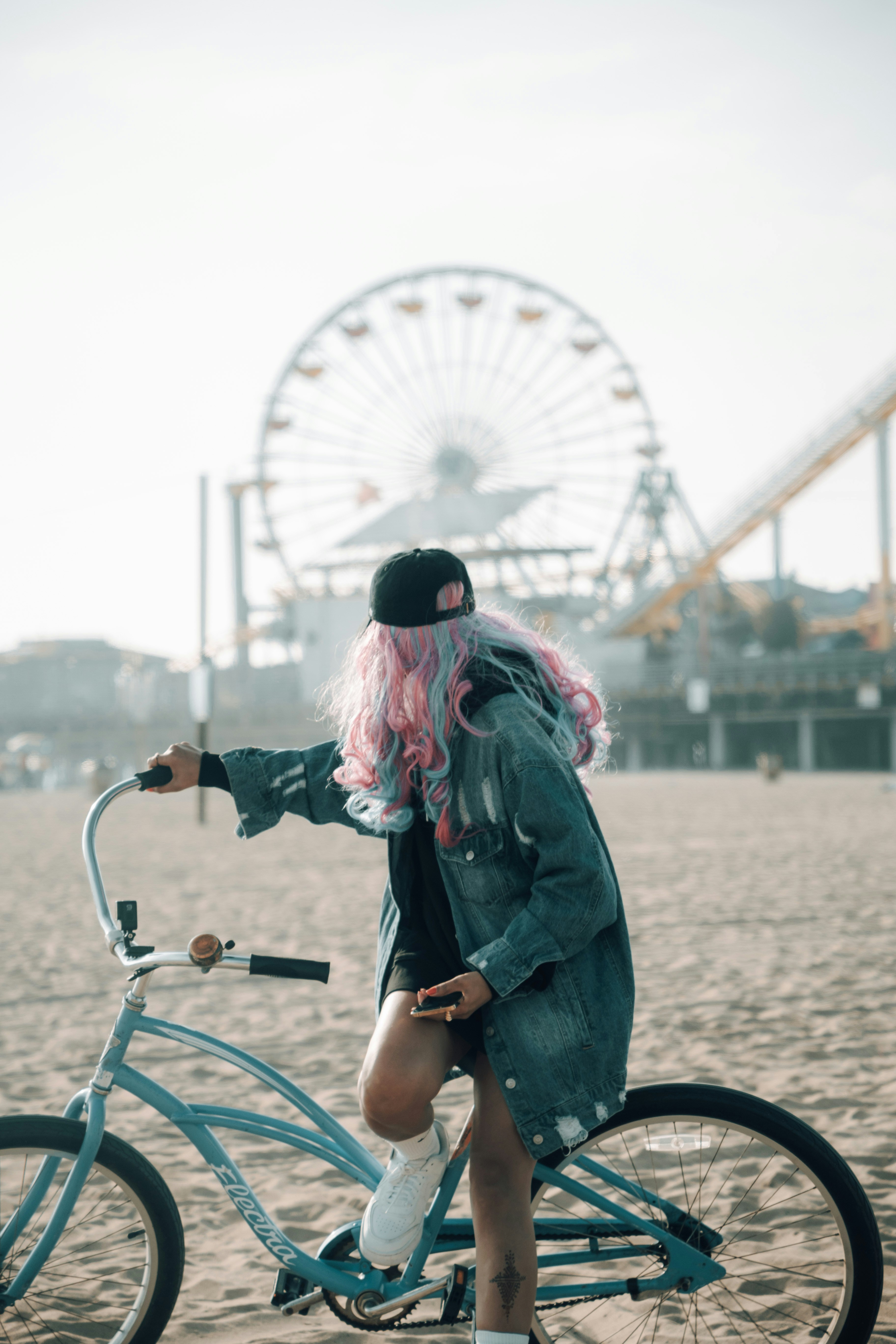 Frau mit rosa Haaren posiert mit einem Fahrrad.