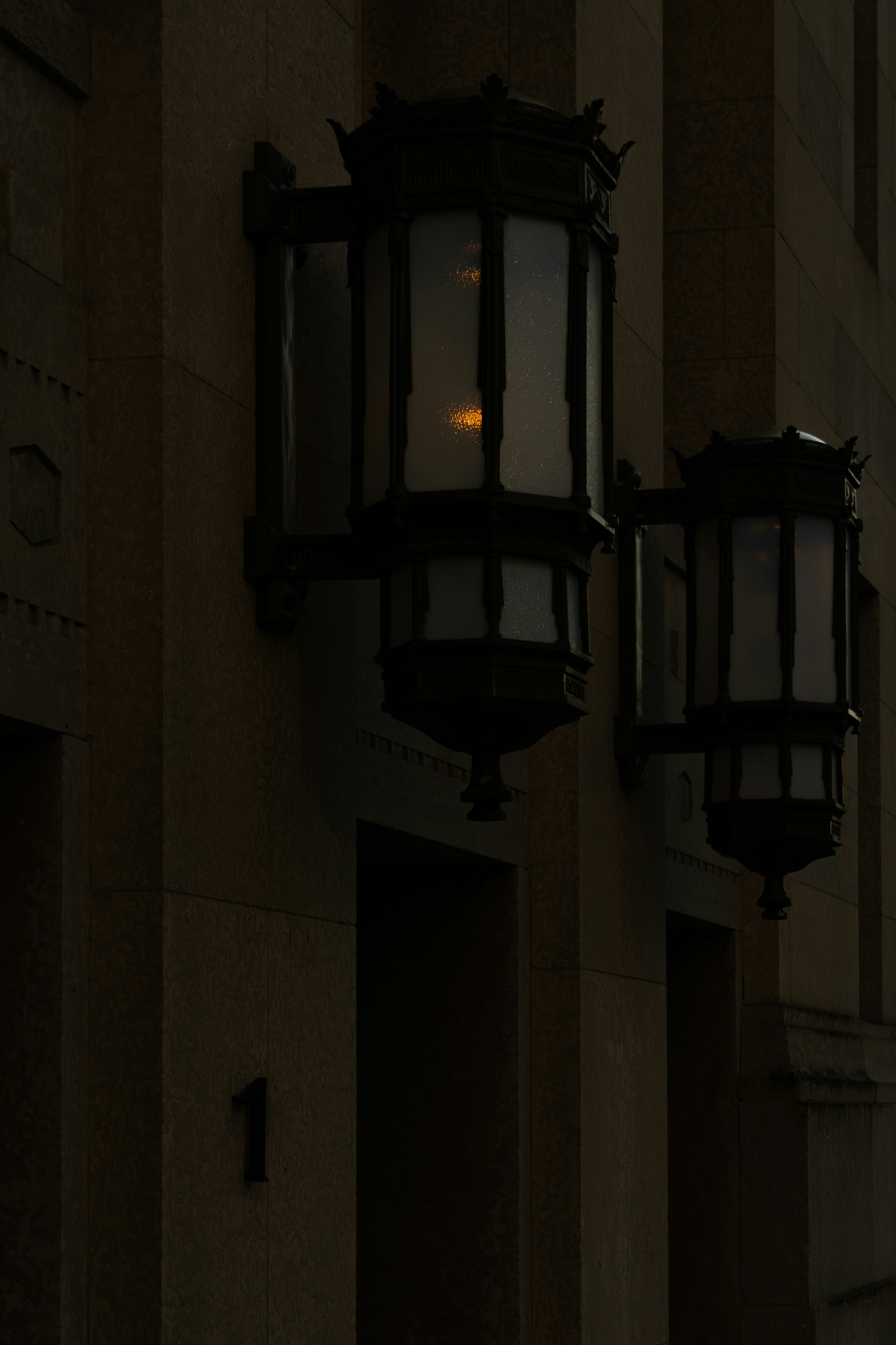 Wall-mounted lanterns illuminate the dark building.