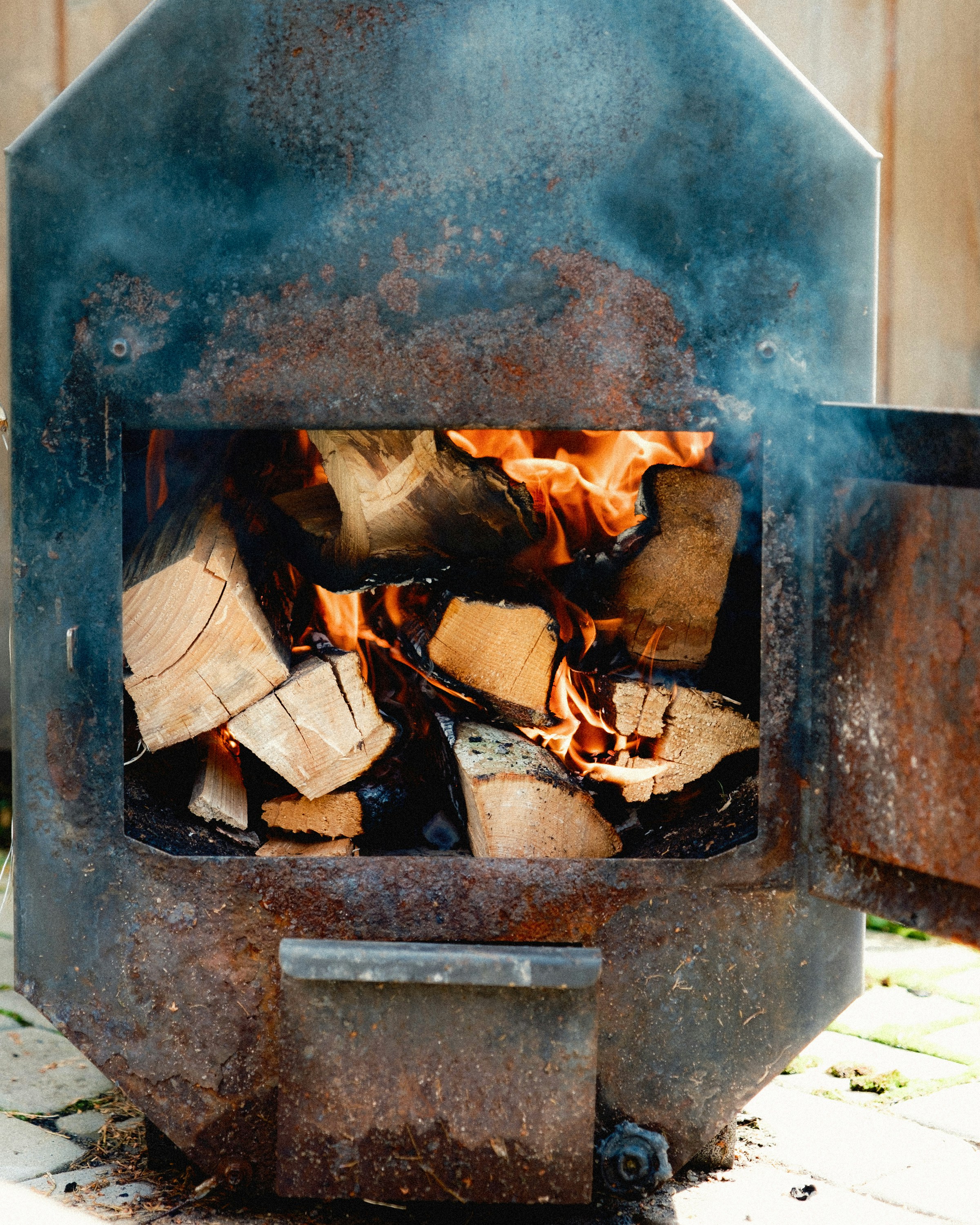 Wood burns brightly inside a metal smoker.