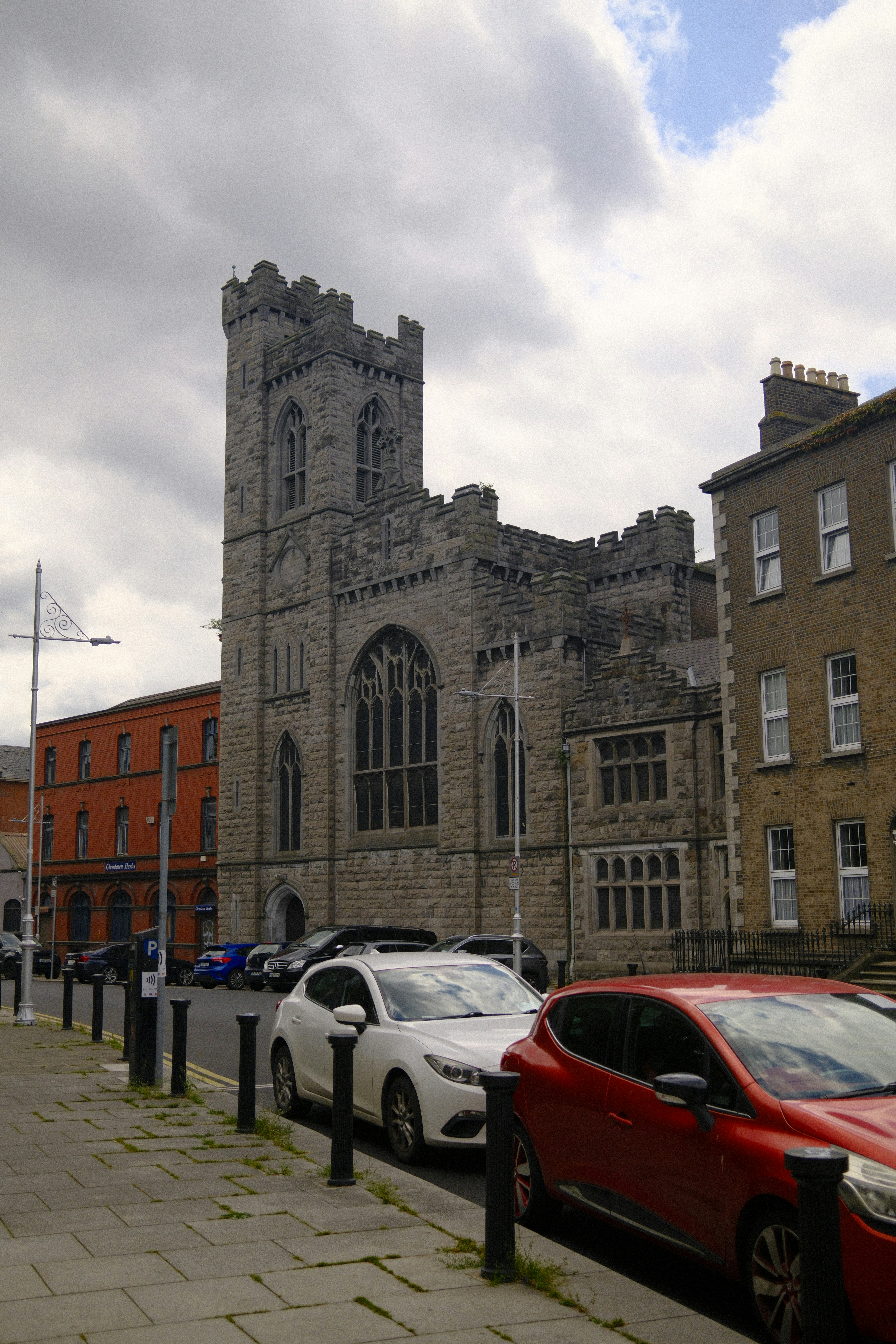 A tall stone building sits next to parked cars.