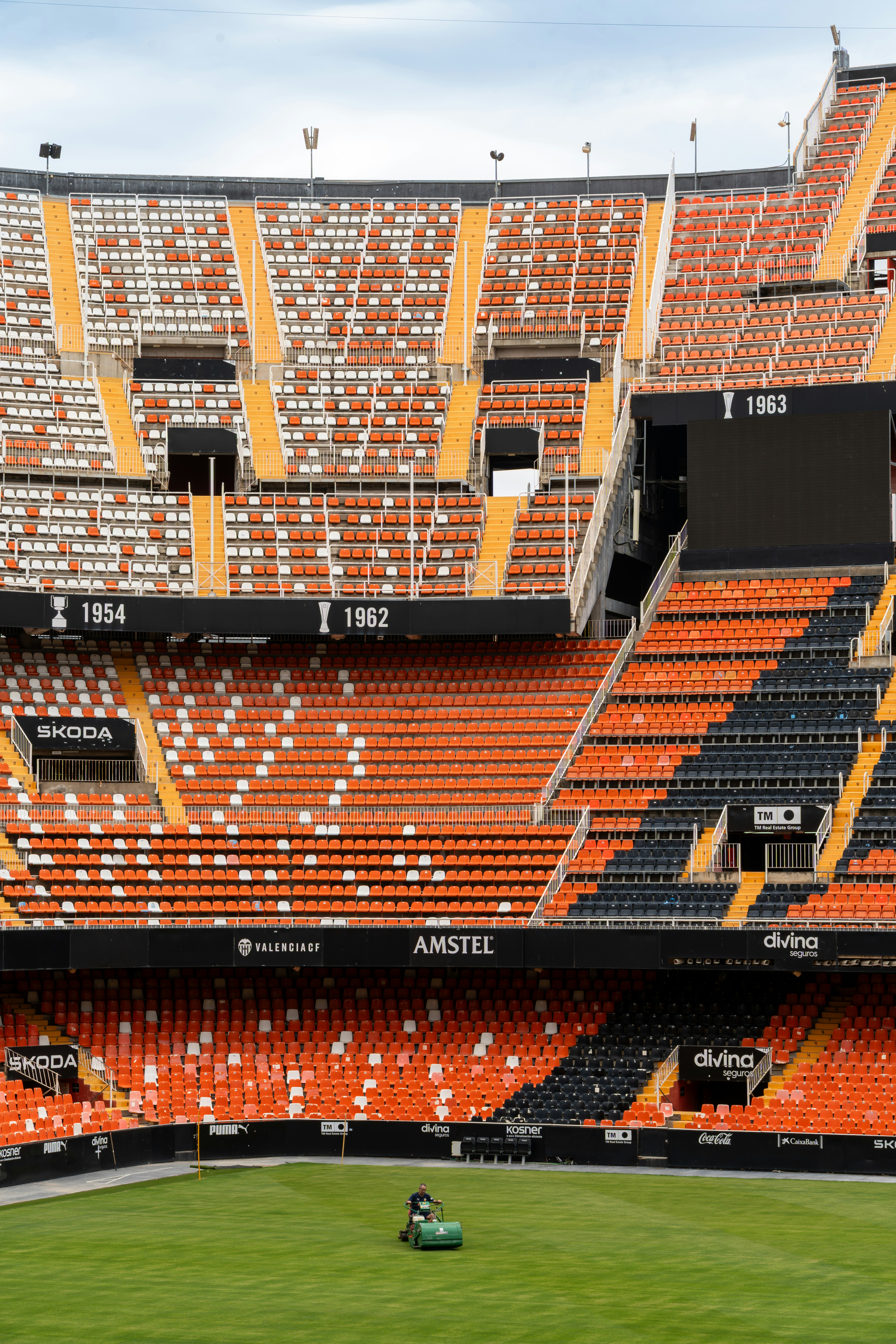 A groundskeeper mows the grass in an empty stadium.