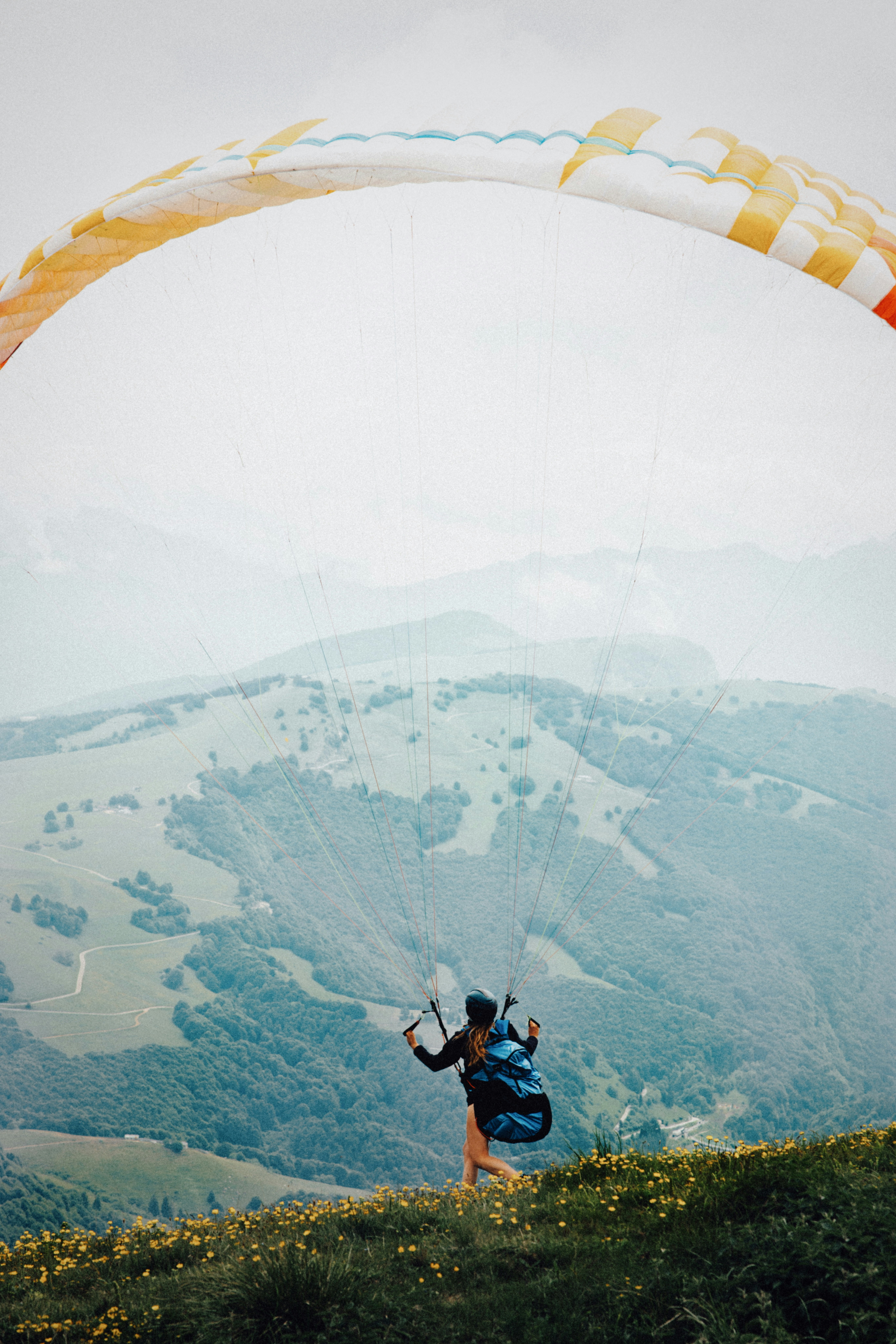 Paraglider prepares to take off over green mountains.
