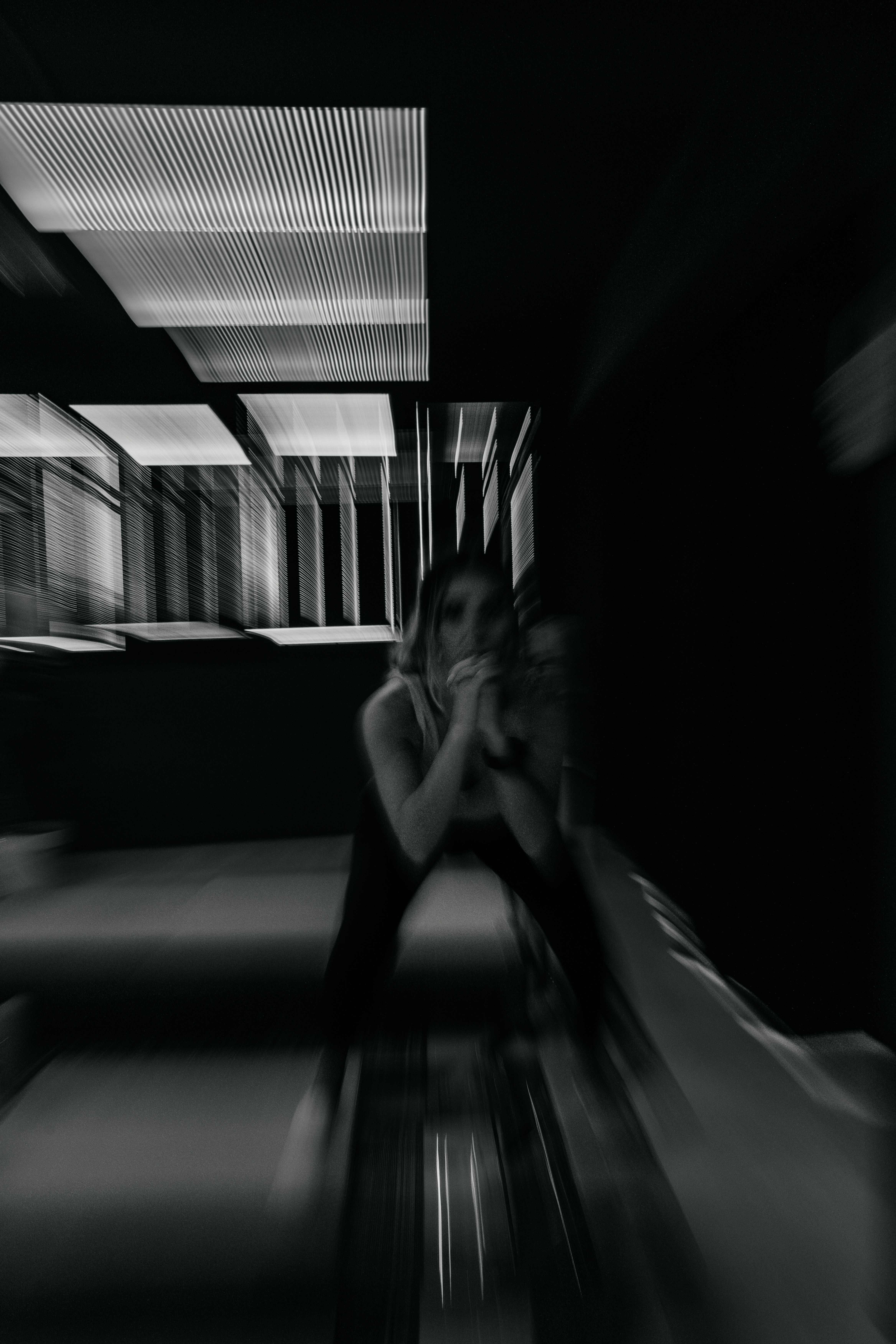 A woman poses in a dark, blurred room.