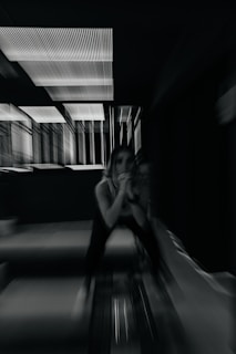 A woman poses in a dark, blurred room.