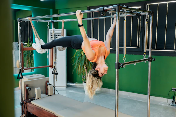Woman performing an advanced Pilates exercise on reformer equipment
