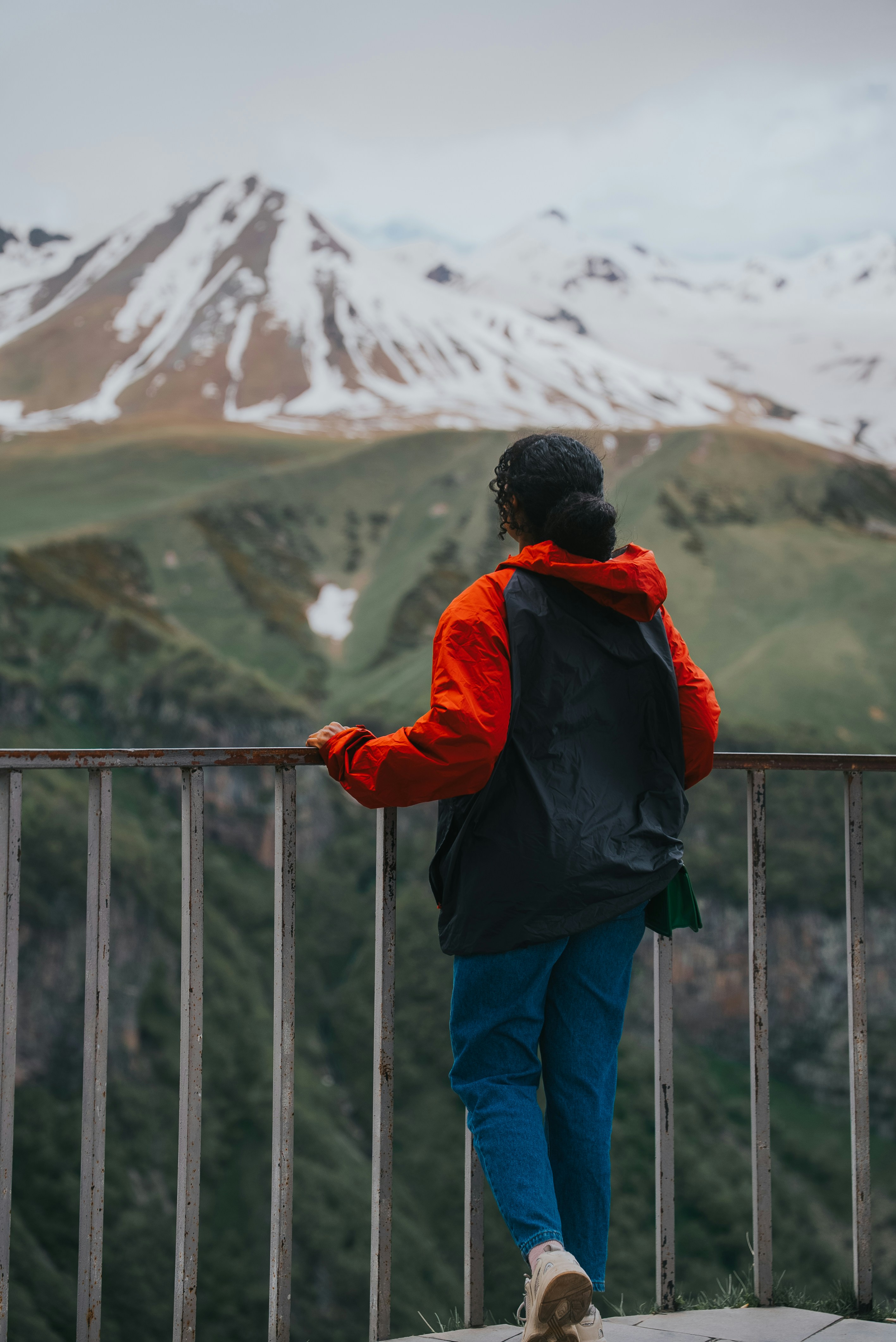 Une personne admirant les montagnes depuis un balcon.