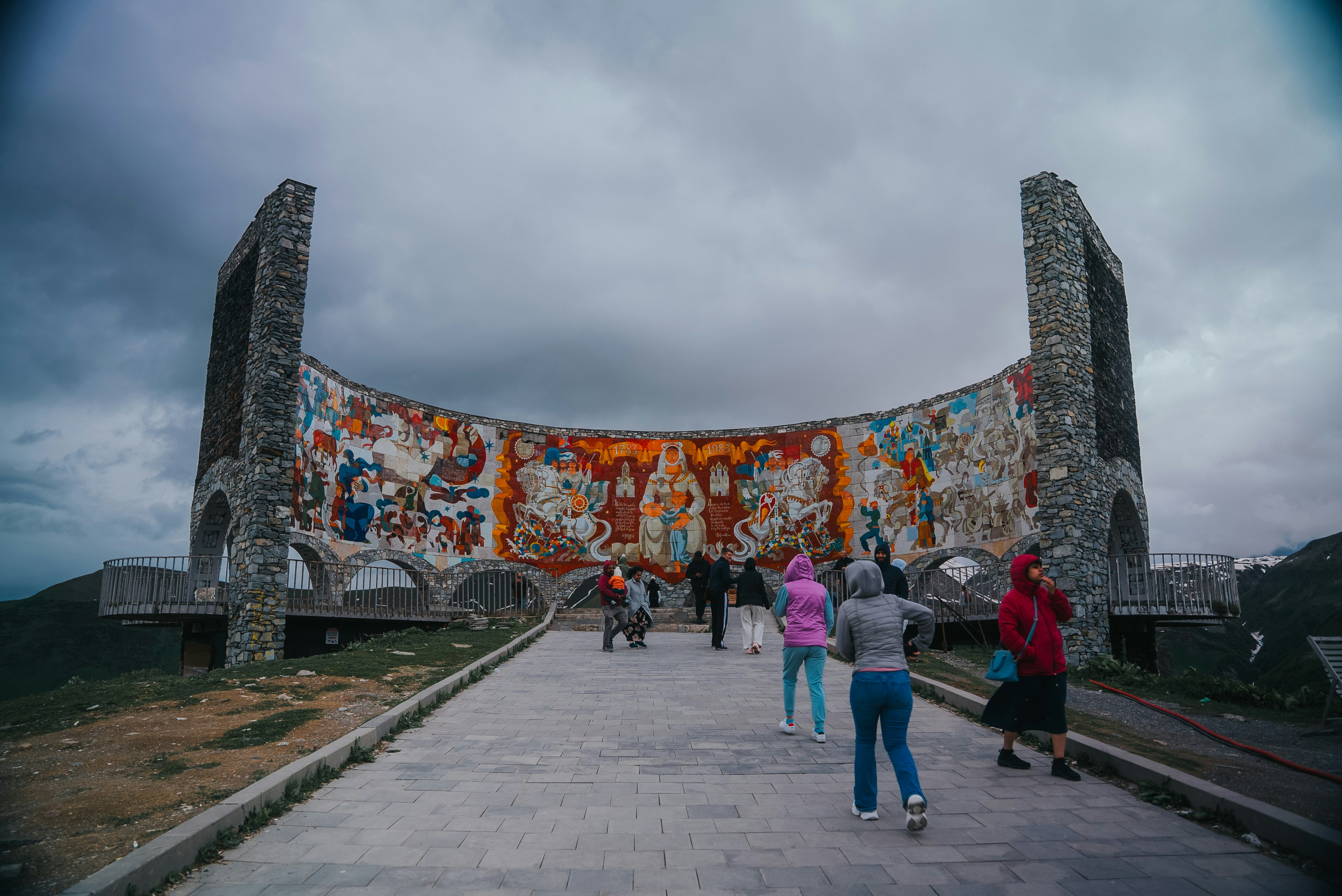Des gens marchent vers une fresque murale par une journée nuageuse.