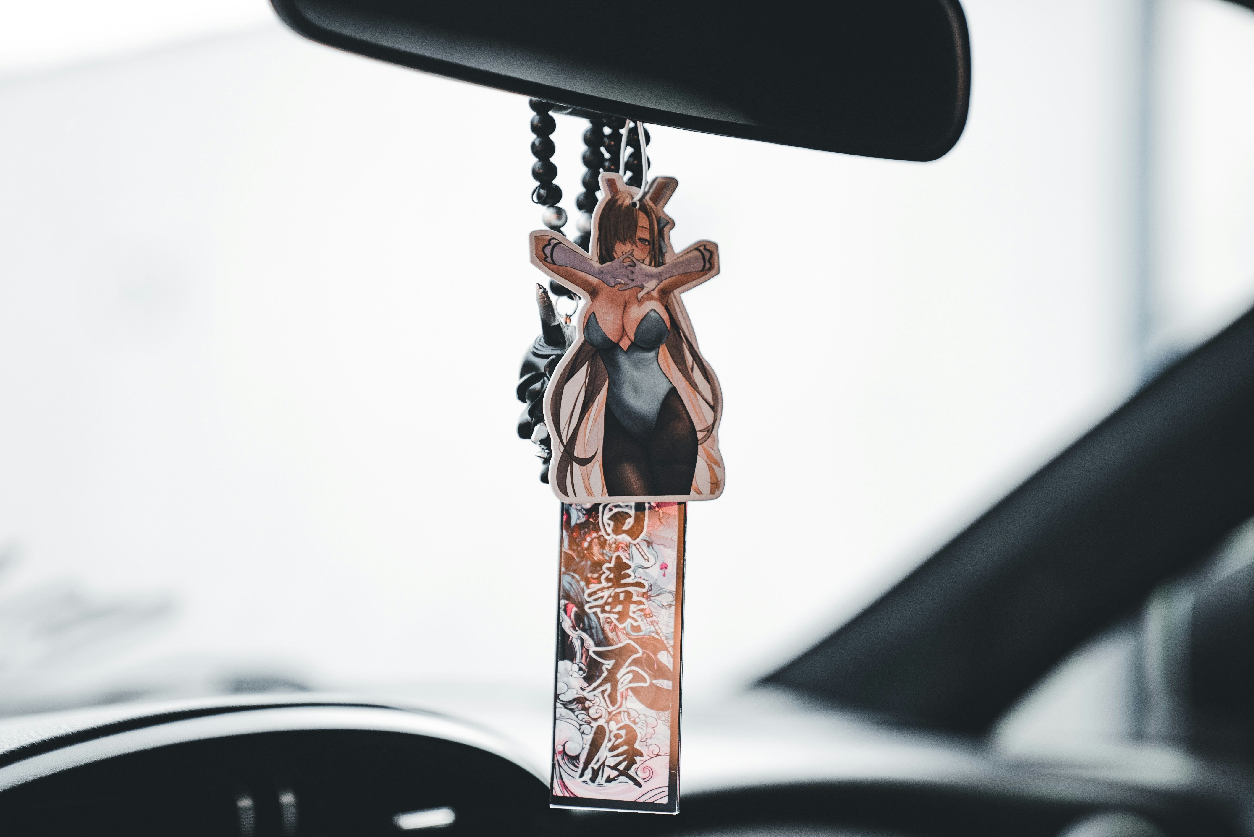 A car's rearview mirror hangs a charm.