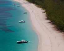 Boats dot a beautiful beach with turquoise waters.