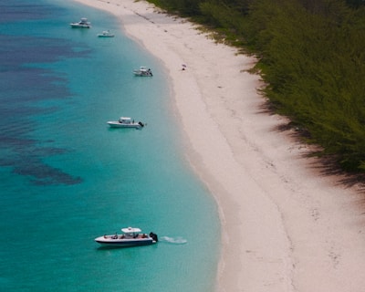 Boats dot a beautiful beach with turquoise waters.